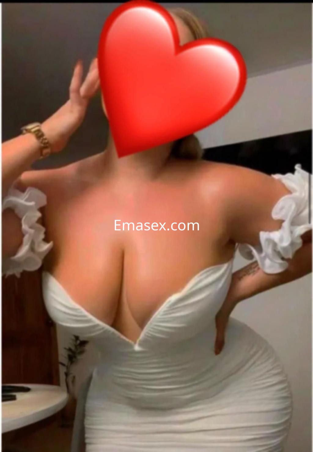 Puta en Almería viste un ajustado vestido blanco con mangas de volantes, posando con una mano en la cadera.