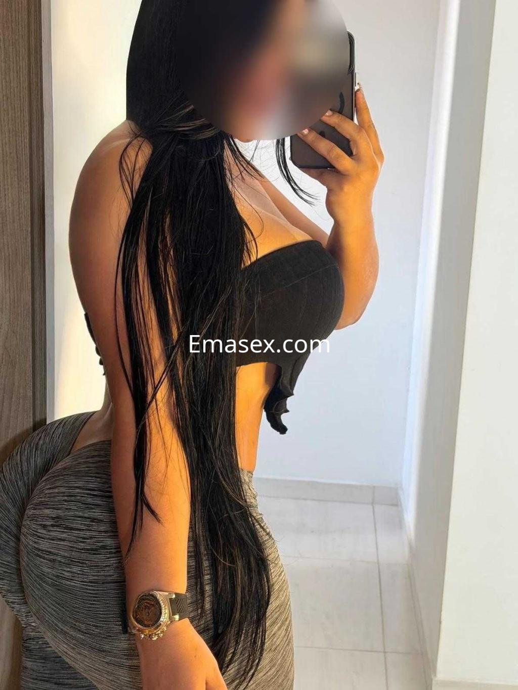 Escort en Córdoba posando de perfil con cabello largo y lacio, vistiendo un top negro y leggings ajustados.