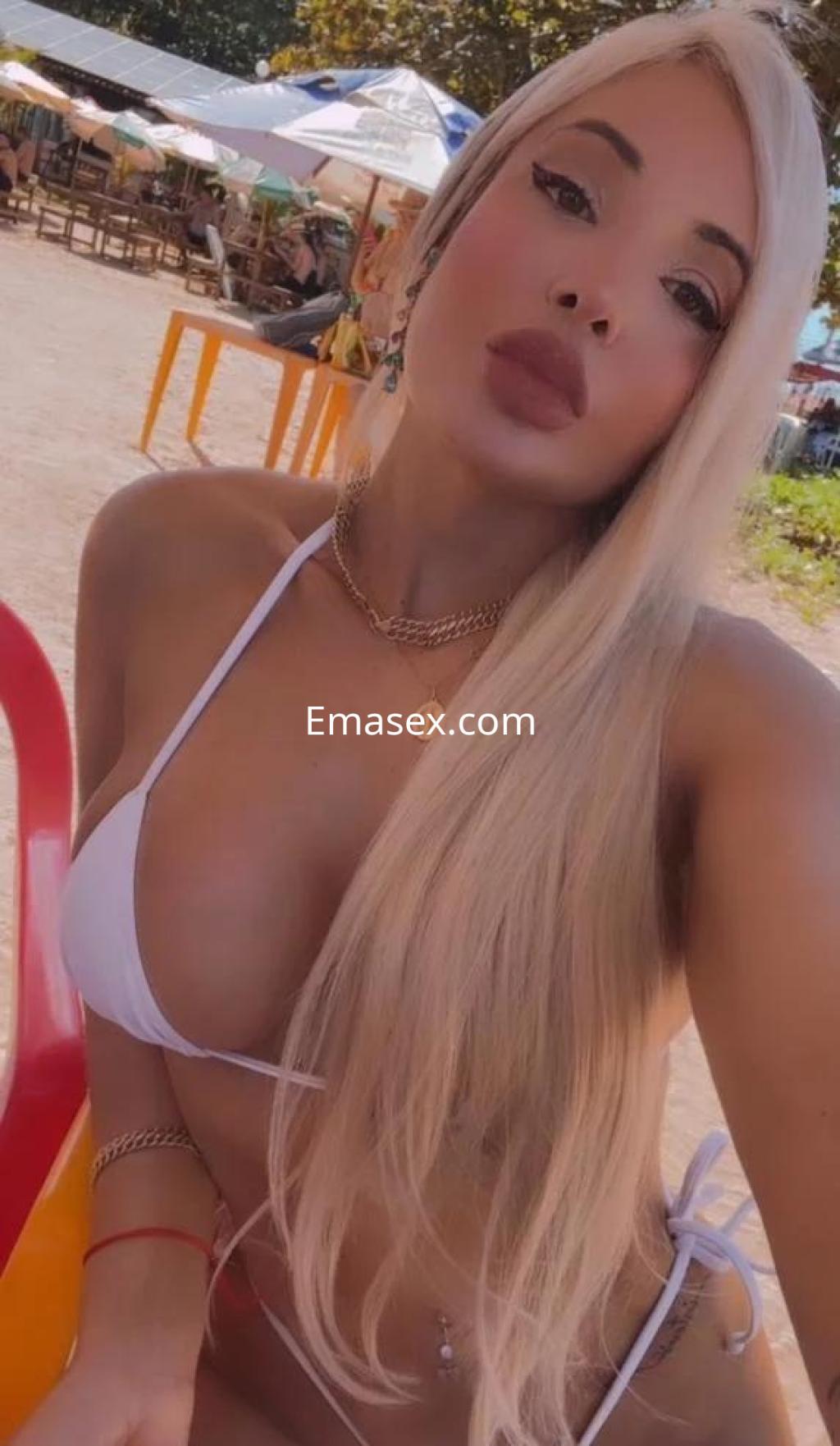 La escort presenta un bikini blanco en una playa de Pontevedra, con cabello largo y lacio, posando sonriente.