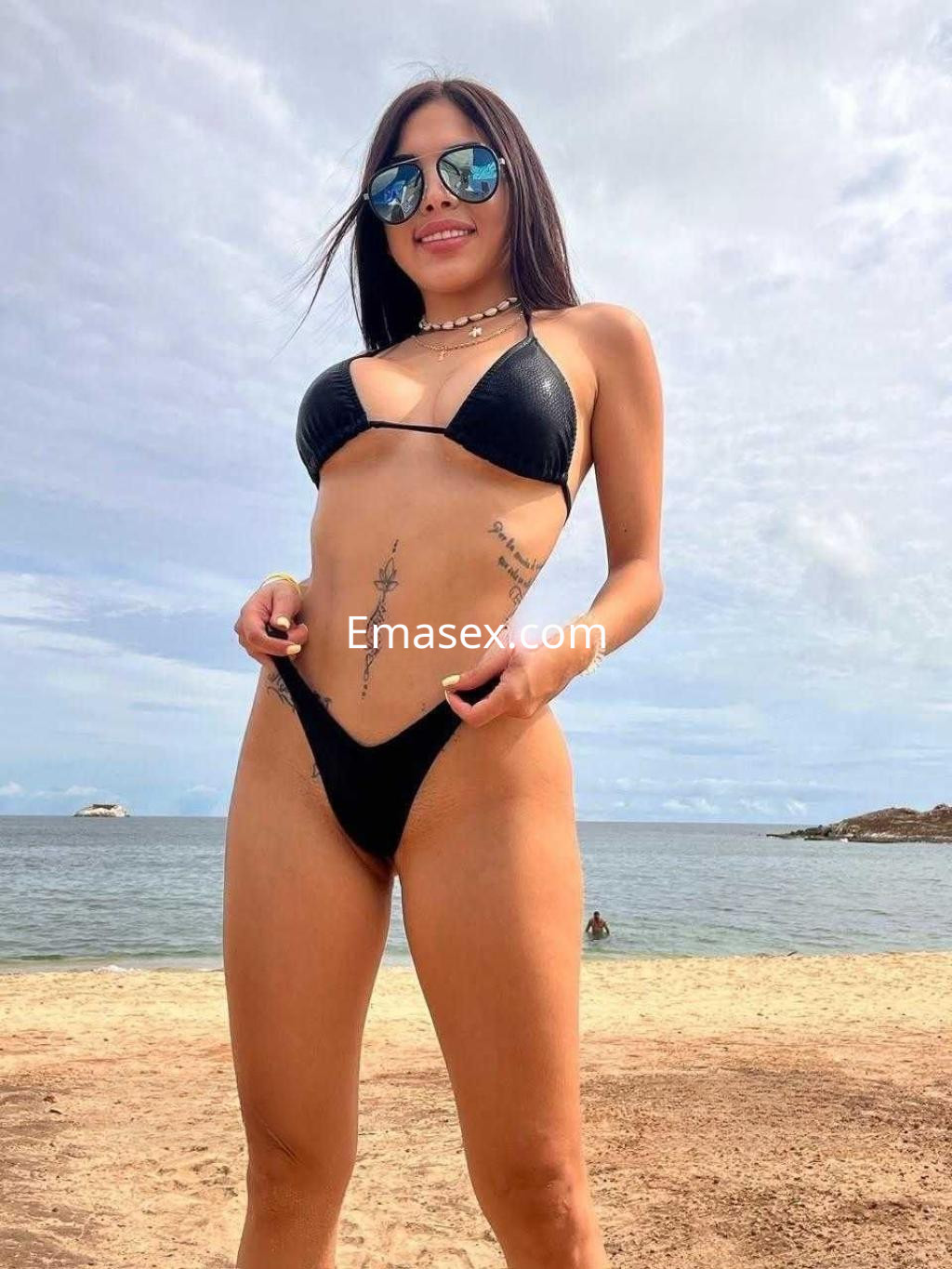 Puta de cabello lacio y oscuro, lleva un bikini negro y gafas de sol en la playa de Vigo.