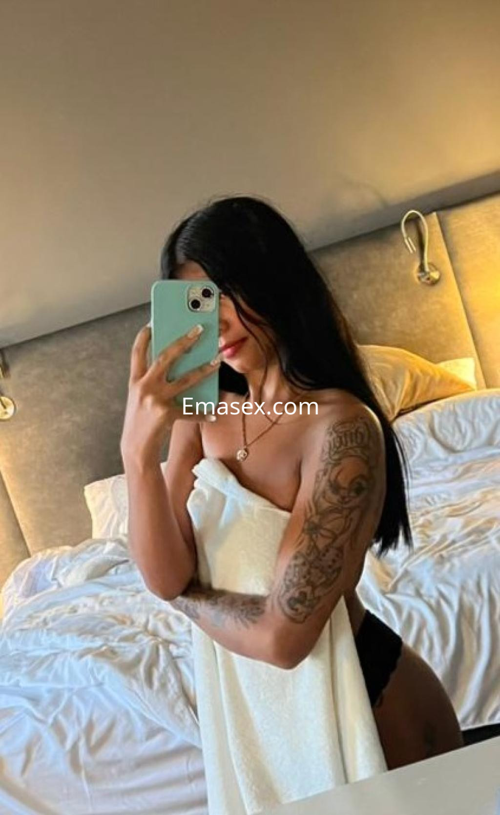 Escort en Madrid con cabello largo y lacio, sosteniendo una toalla, en una habitación de hotel moderna.