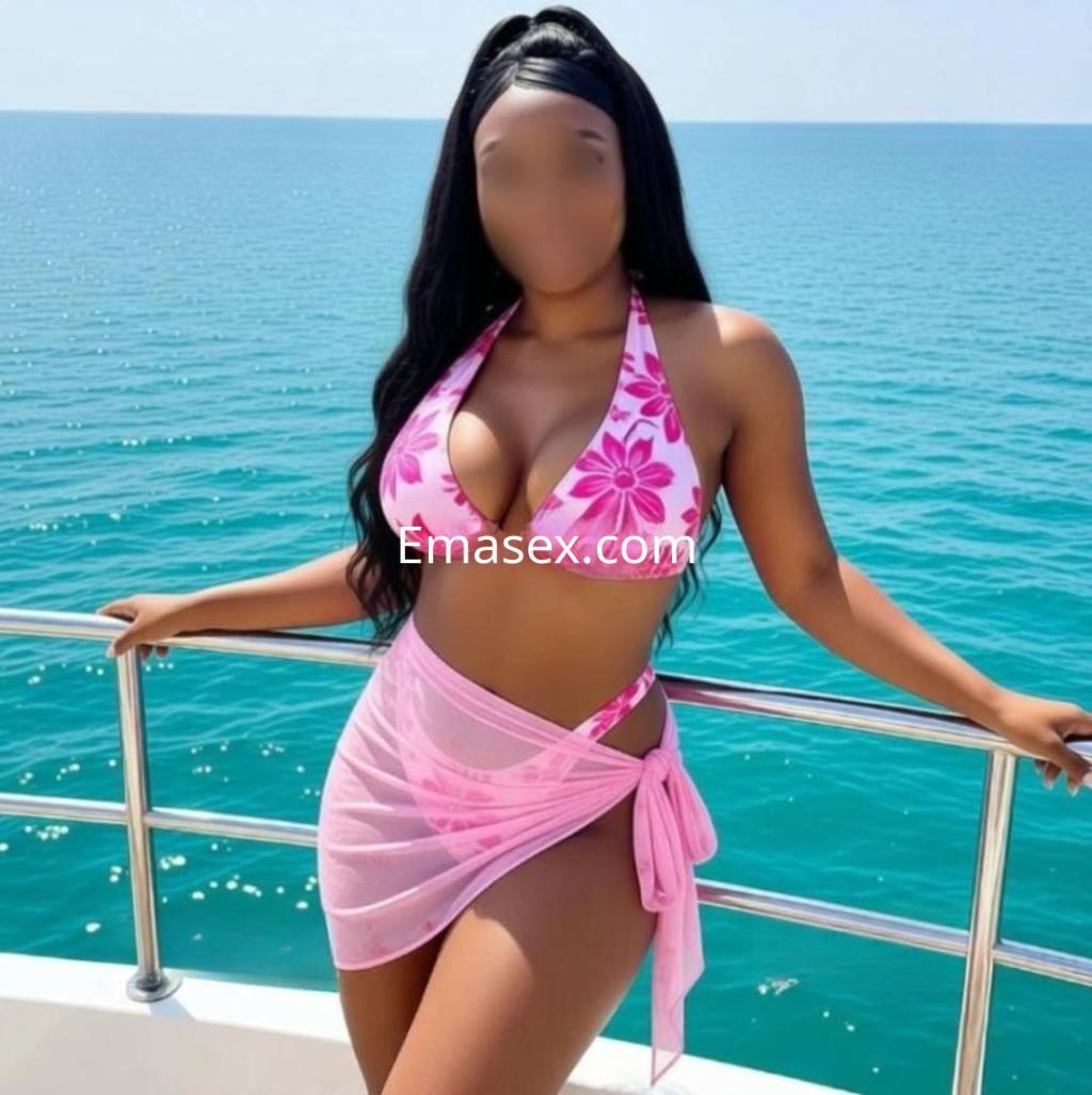Puta posando en un bikini rosa con estampado floral y pareo transparente, frente al mar en Albacete.