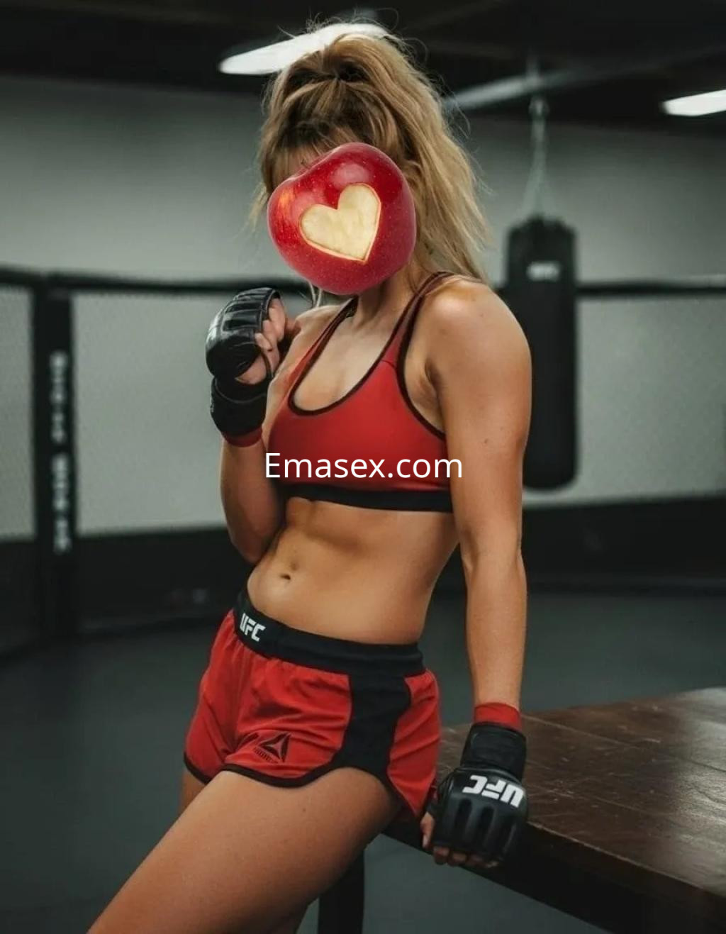 Puta en Oviedo vestida con top rojo y shorts, posando en un gimnasio con guantes de boxeo.