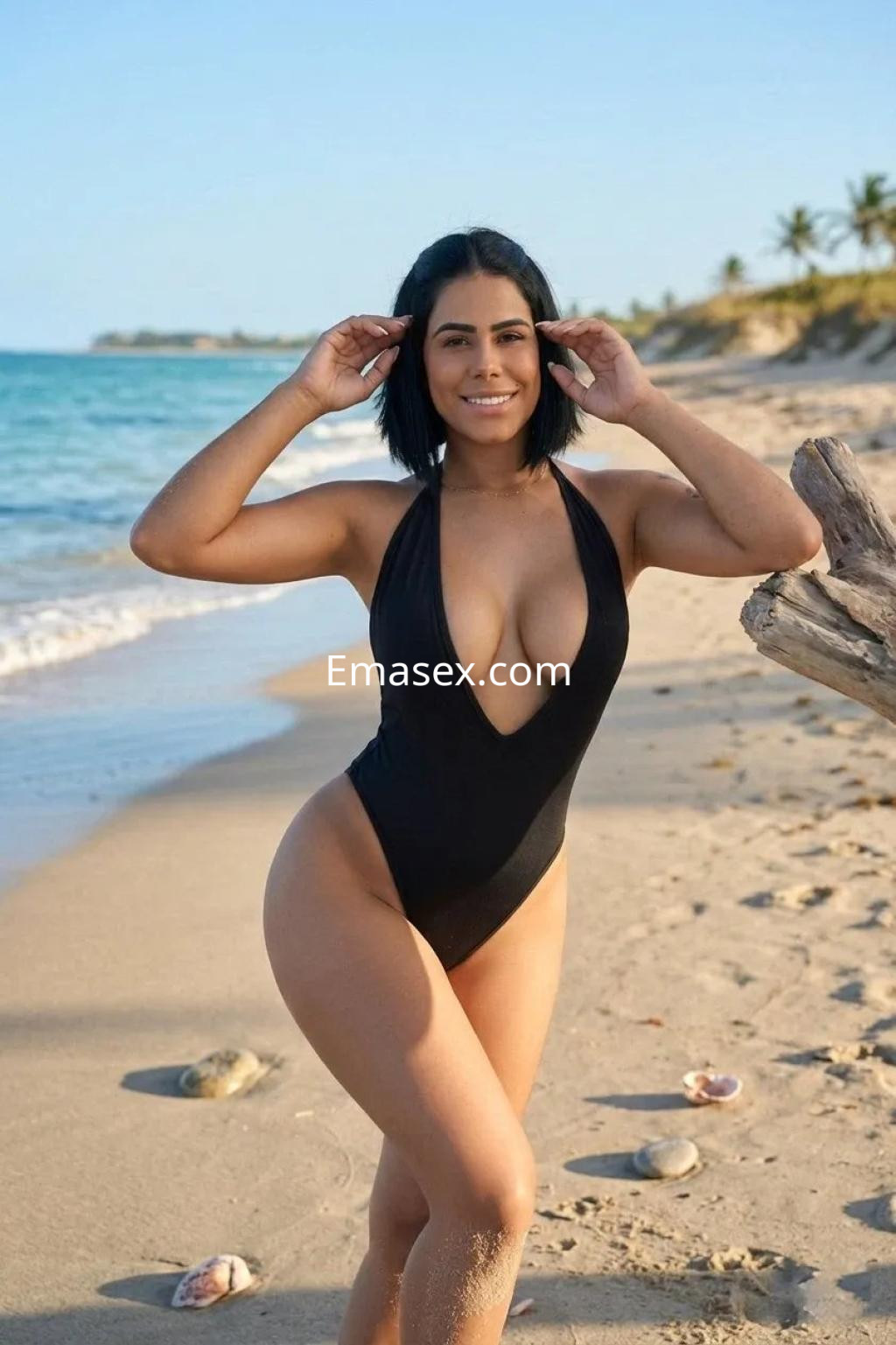 Puta en Valencia luciendo un bañador negro, posando con confianza en la playa bajo el sol.