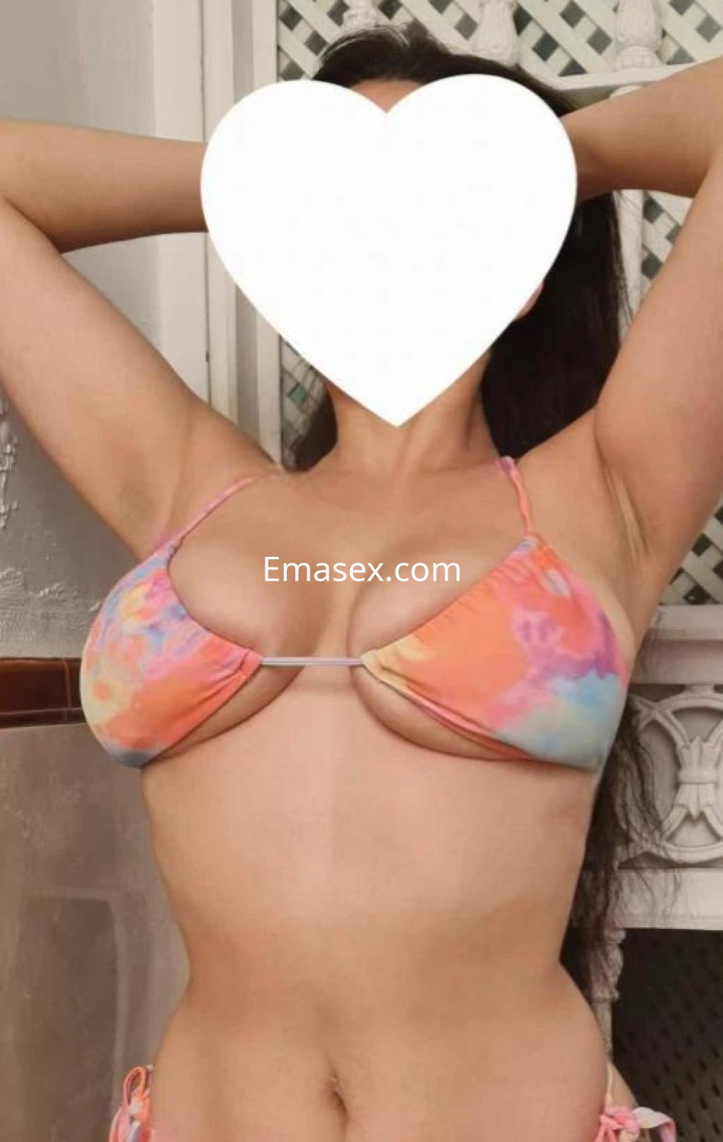 Puta en Sevilla, con cabello largo y lacio, viste un bikini de colores pastel mientras posa con los brazos levantados.