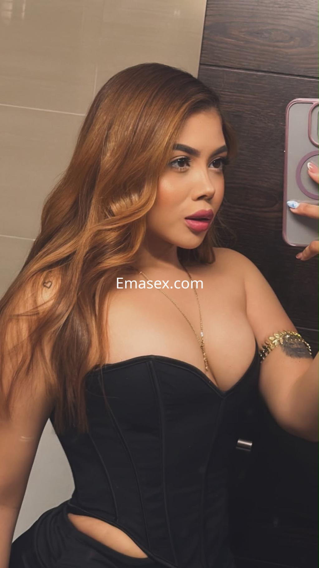 Escort en Málaga posando con un corsé negro y cabello ondulado, mostrando un look elegante y seductor.