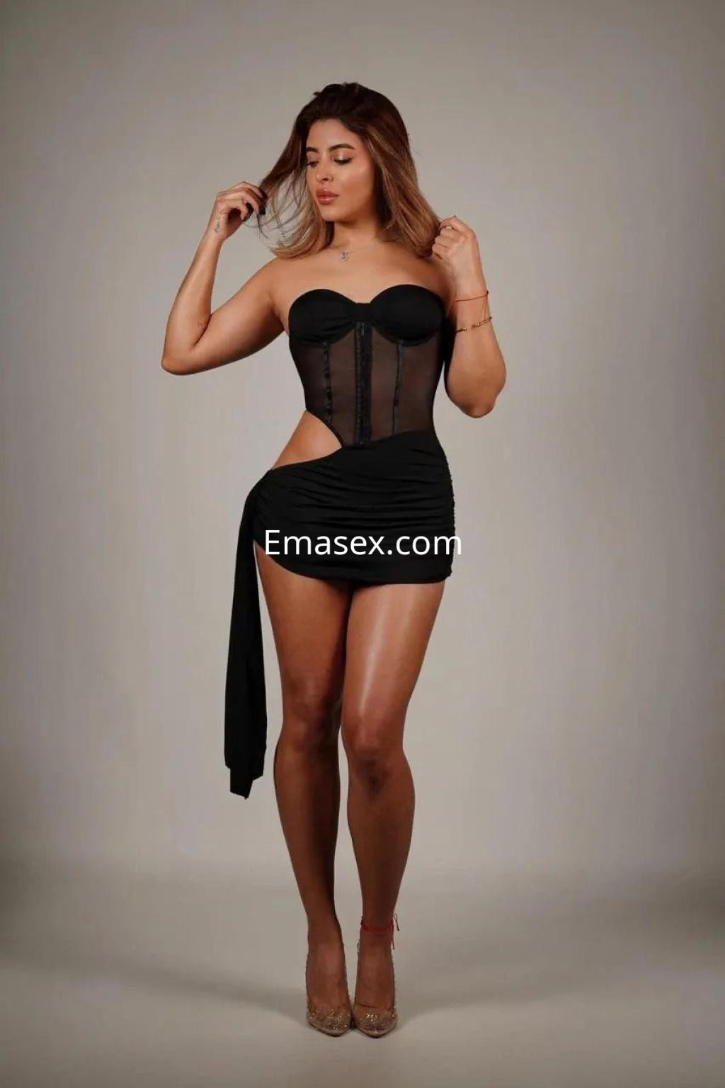 Puta en Palma de Mallorca viste un vestido negro ajustado que resalta su figura, con tacones y cabello suelto.