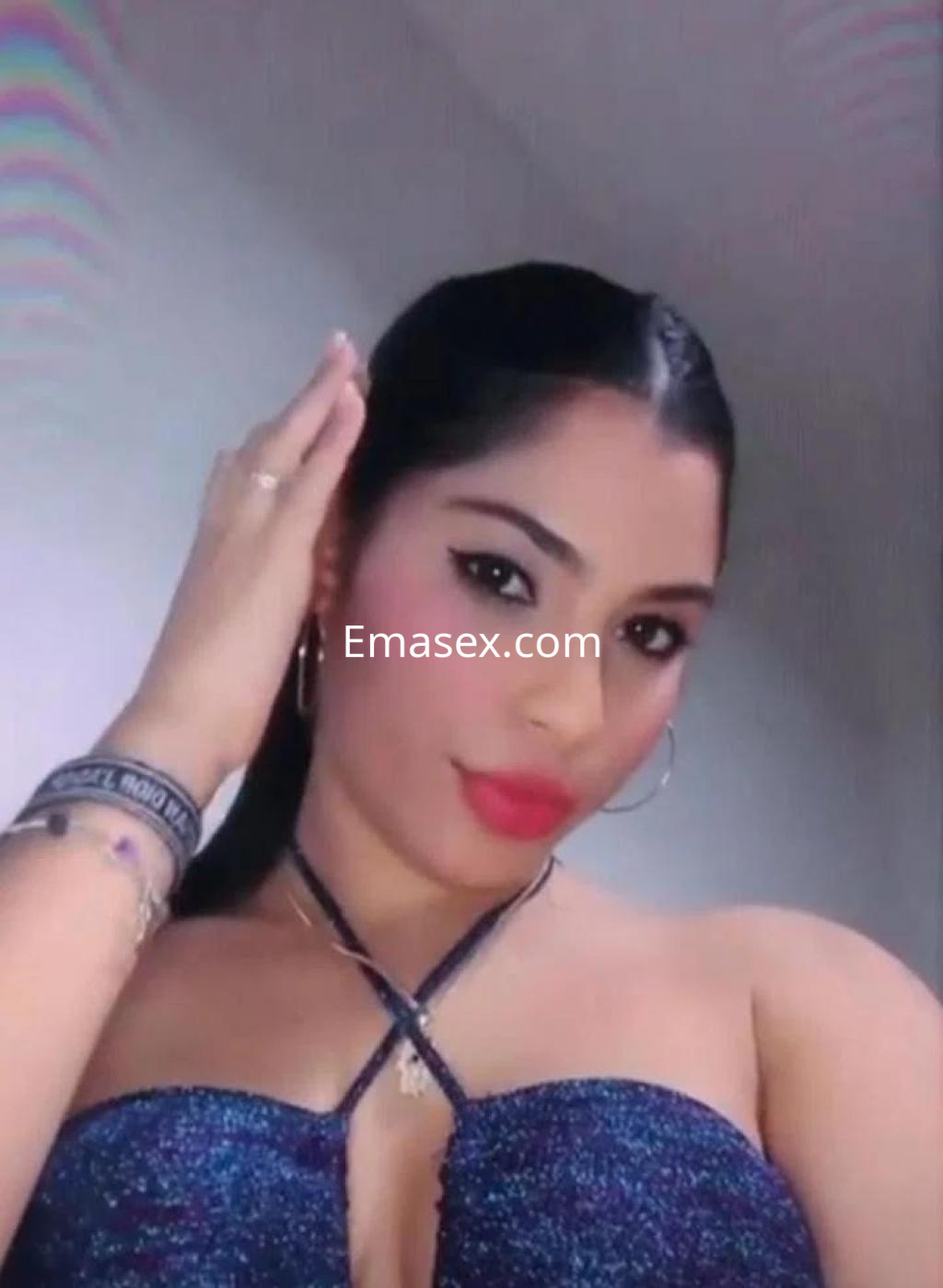 Escort en Cádiz con cabello largo y lacio, vistiendo un top brillante, posando mientras se toca el cabello.