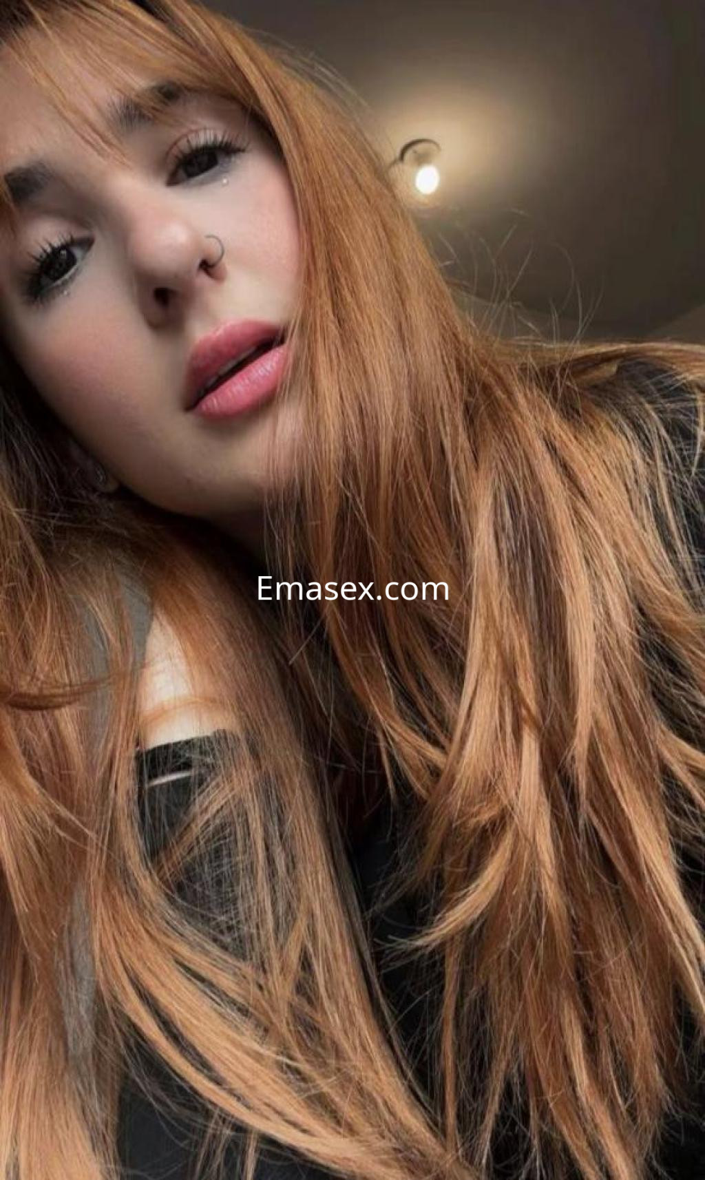Escort con cabello largo y suelto, rostro en primer plano, luz suave y fondo neutro en Castellón.