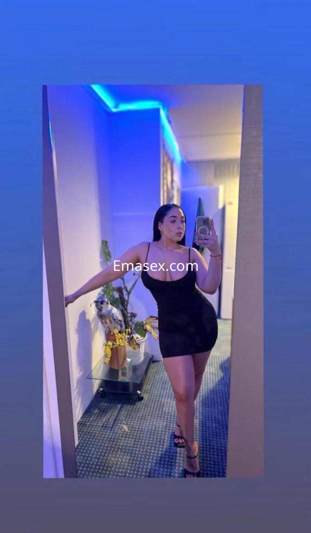 La puta posa con un vestido negro ajustado en un ambiente iluminado con luces azules en Las Palmas.