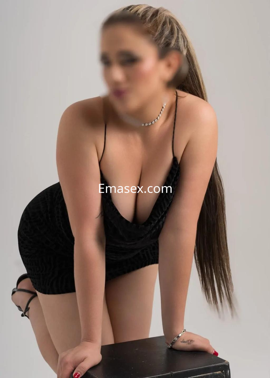 Puta en Valencia se inclina sobre un soporte, luciendo un vestido negro ajustado y cabello largo.