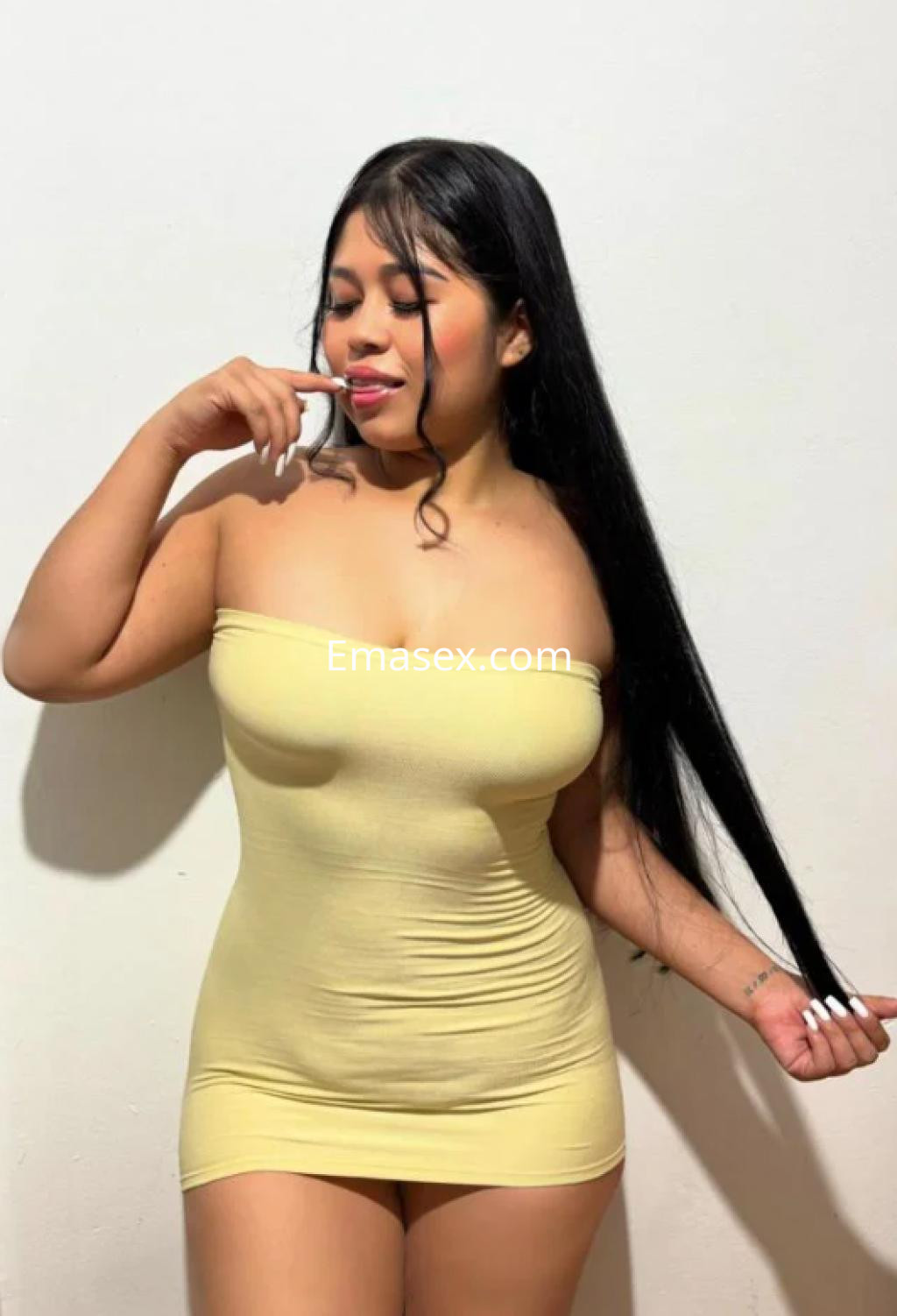 Escort en Girona con cabello largo y lacio, vistiendo un vestido ajustado amarillo y posando de forma coqueta.