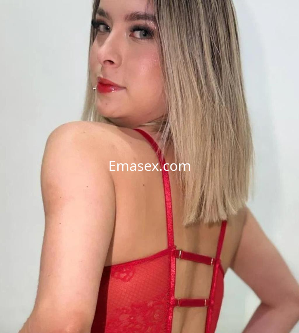 La puta luce un body rojo de encaje con detalles en la espalda, posando de perfil en Alicante.