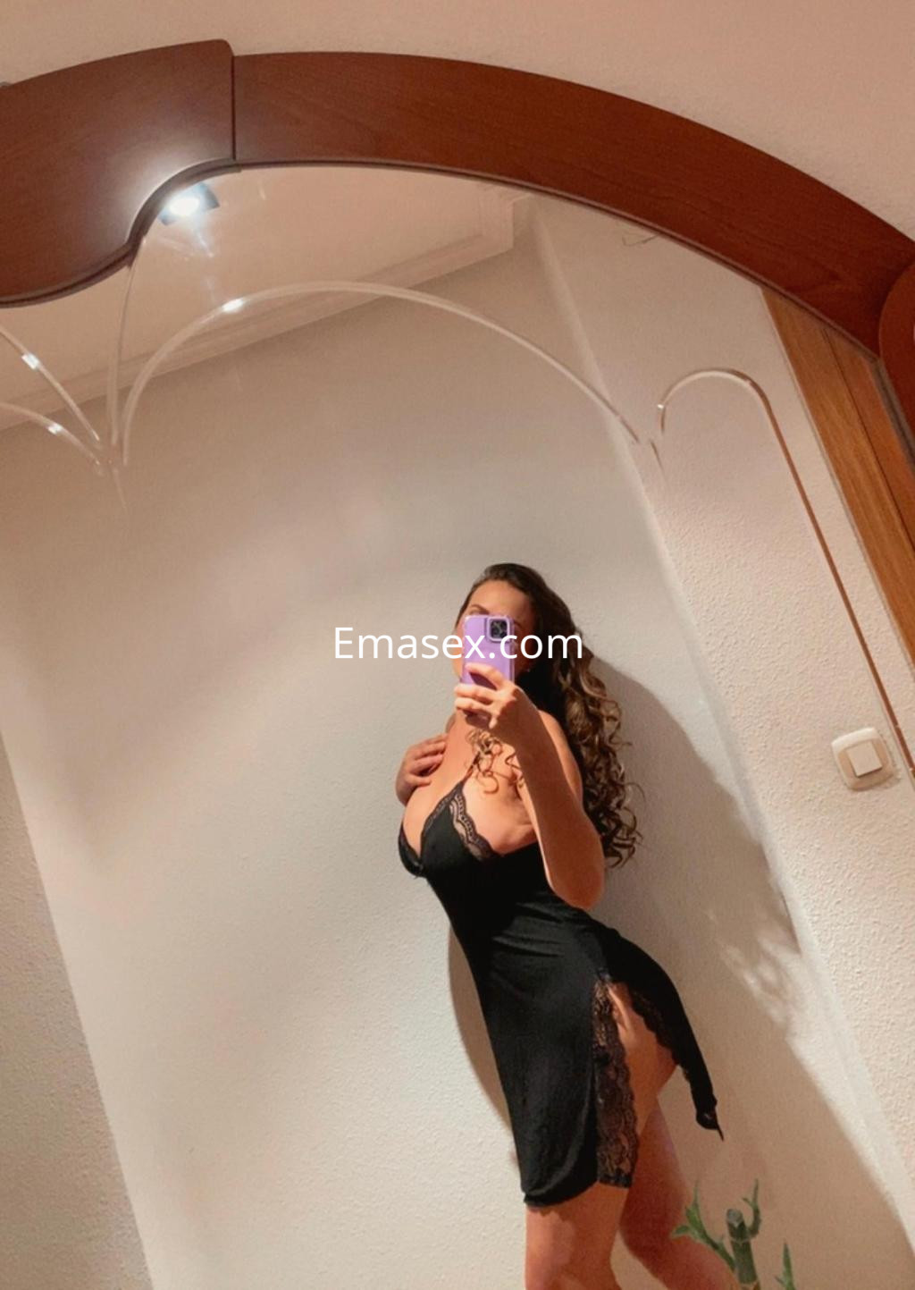 La puta en León se muestra en un vestido negro ajustado con encaje, posando frente a un espejo.