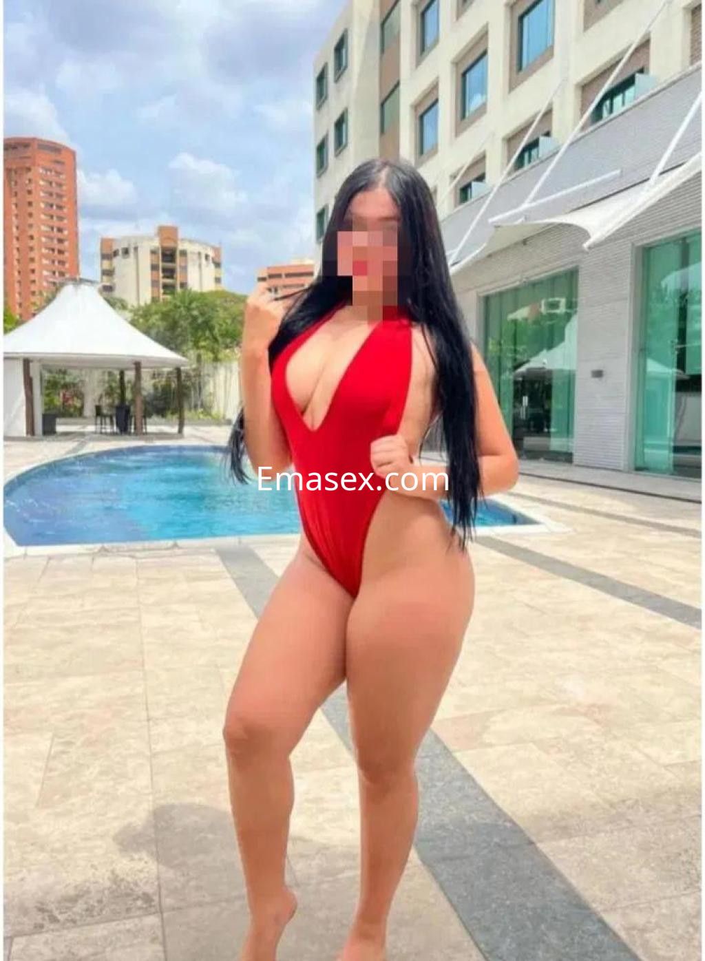 Escort posando en traje de baño rojo junto a una piscina en Huelva, con cabello largo y oscuro.