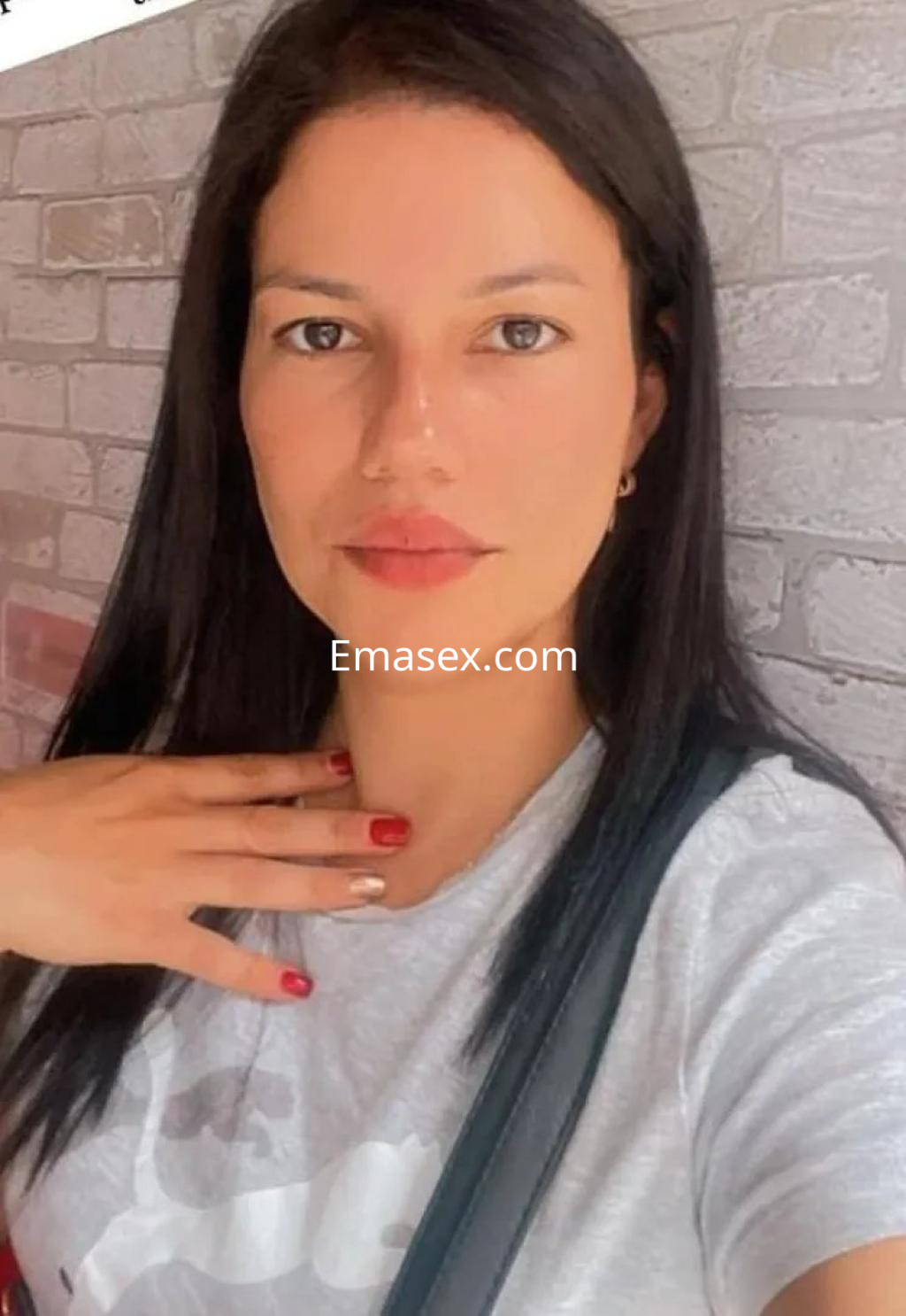 Escort en Toledo con cabello largo y lacio, luciendo una camiseta gris y un maquillaje natural.