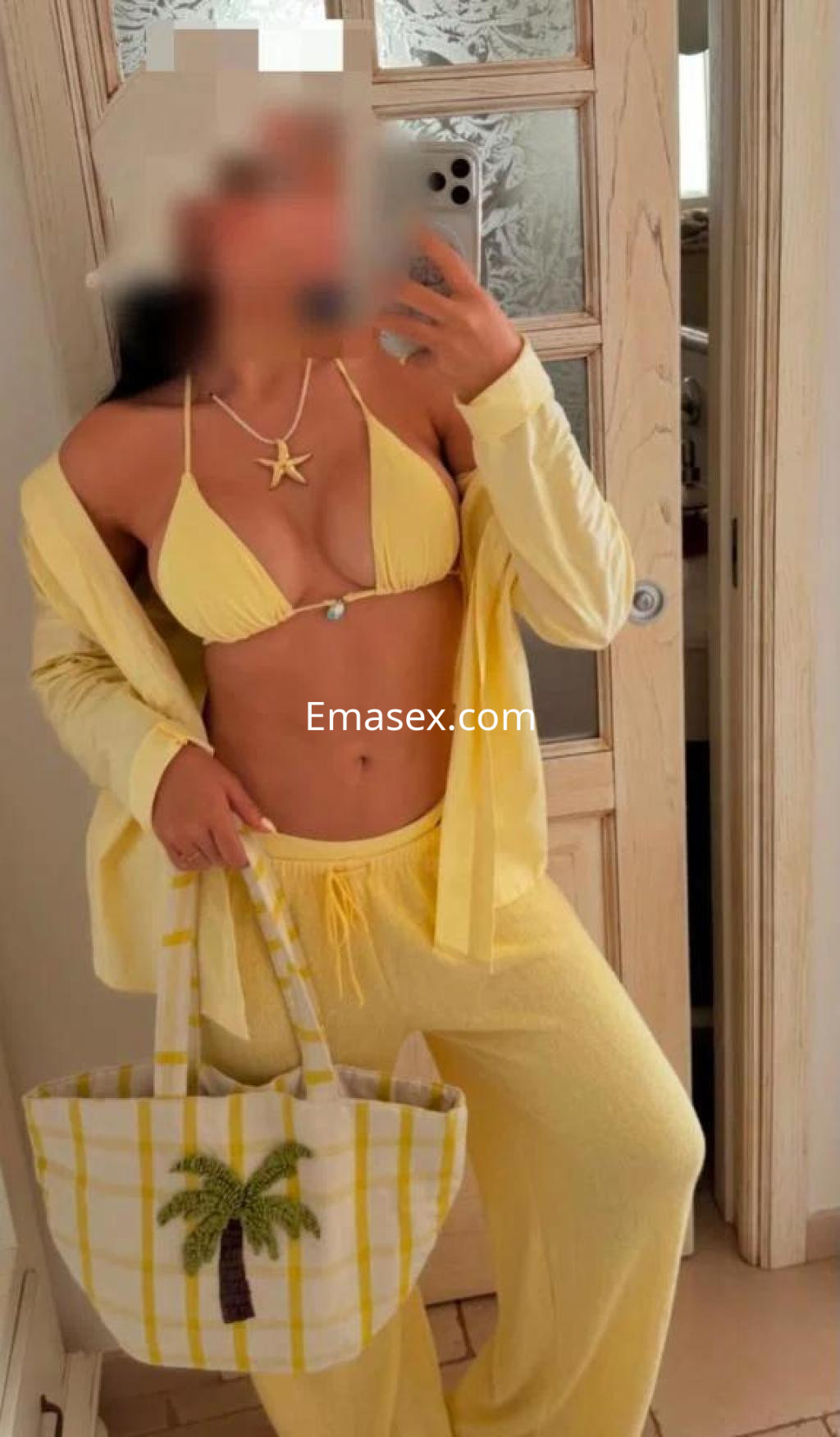 La puta viste un conjunto amarillo de bikini y pantalones, sosteniendo un bolso de rayas en Albacete.