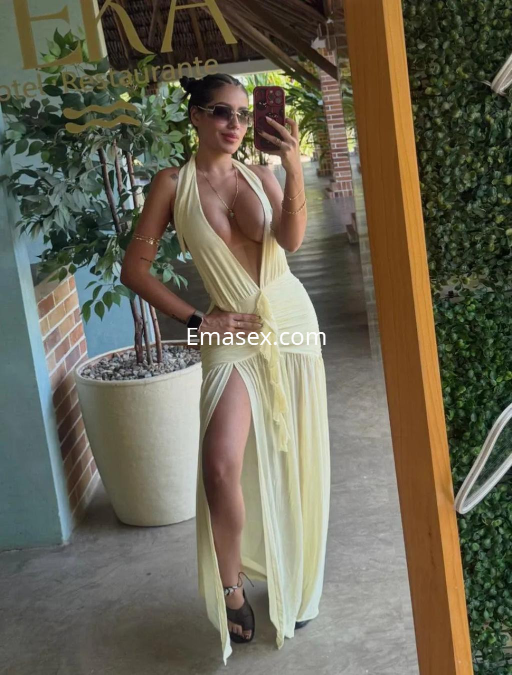 La puta posa con un vestido largo y ligero de color amarillo, destacando su figura en un ambiente de Palma de Mallorca.