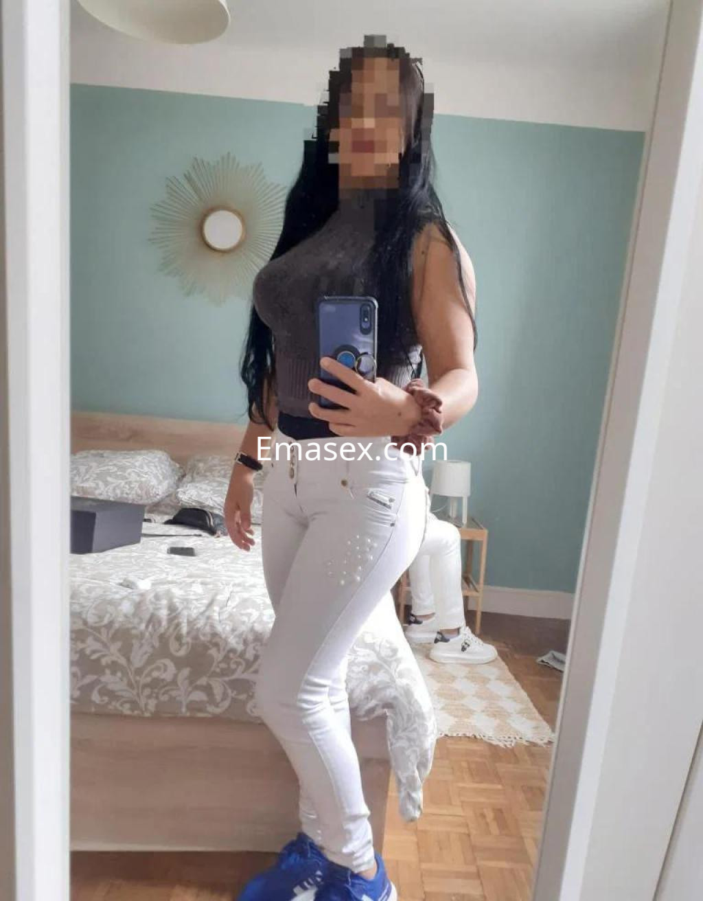 La puta en Valencia lleva un top gris y jeans blancos, mostrando su figura en un ambiente acogedor.