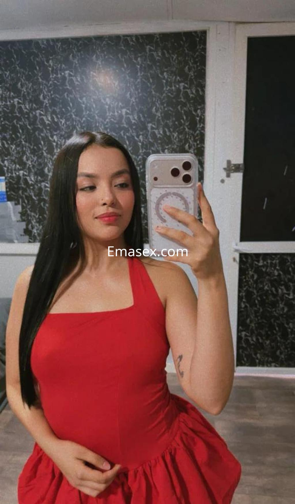 La puta en Valencia se muestra con un vestido rojo ajustado, cabello largo y lacio, y sonríe a la cámara.