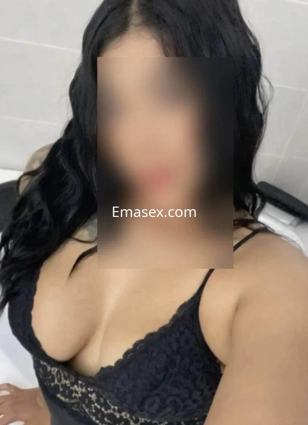 Puta con cabello oscuro y ondulado, viste un sujetador negro que resalta su figura en un entorno de baño en Zaragoza.