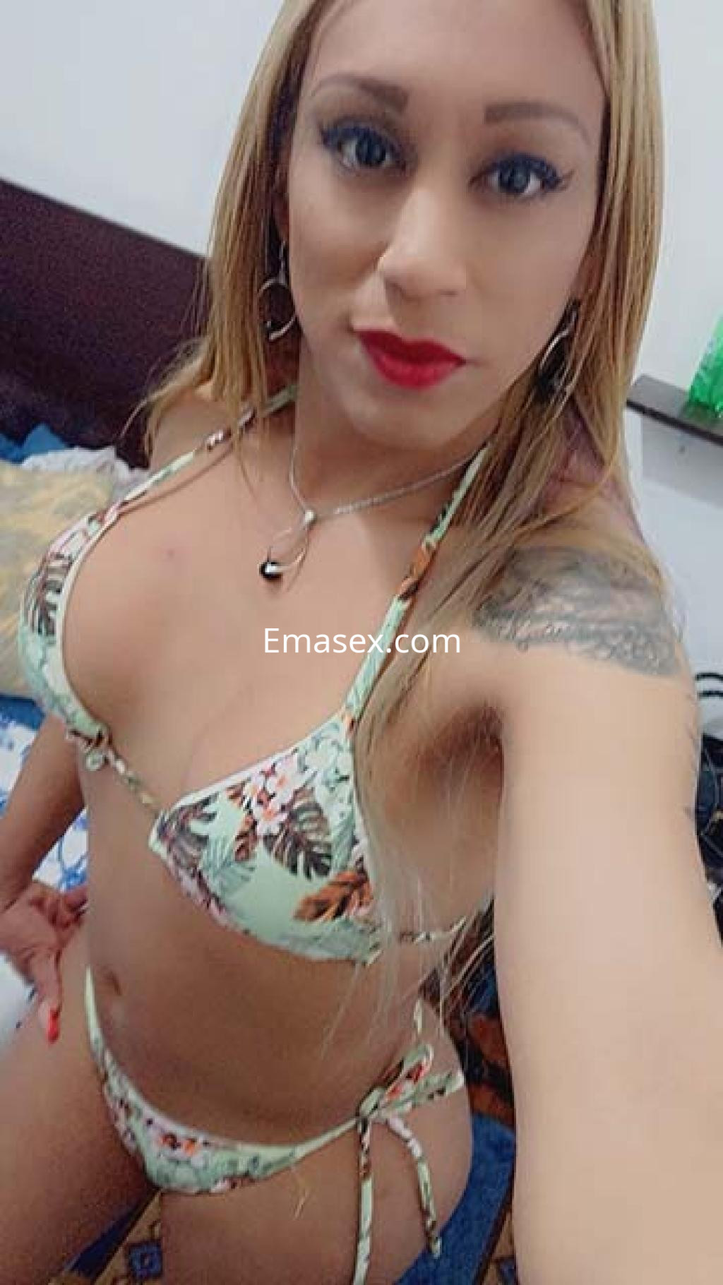 Puta trans en Logroño, luciendo un bikini verde con estampado floral y labios rojos en un ambiente interior.