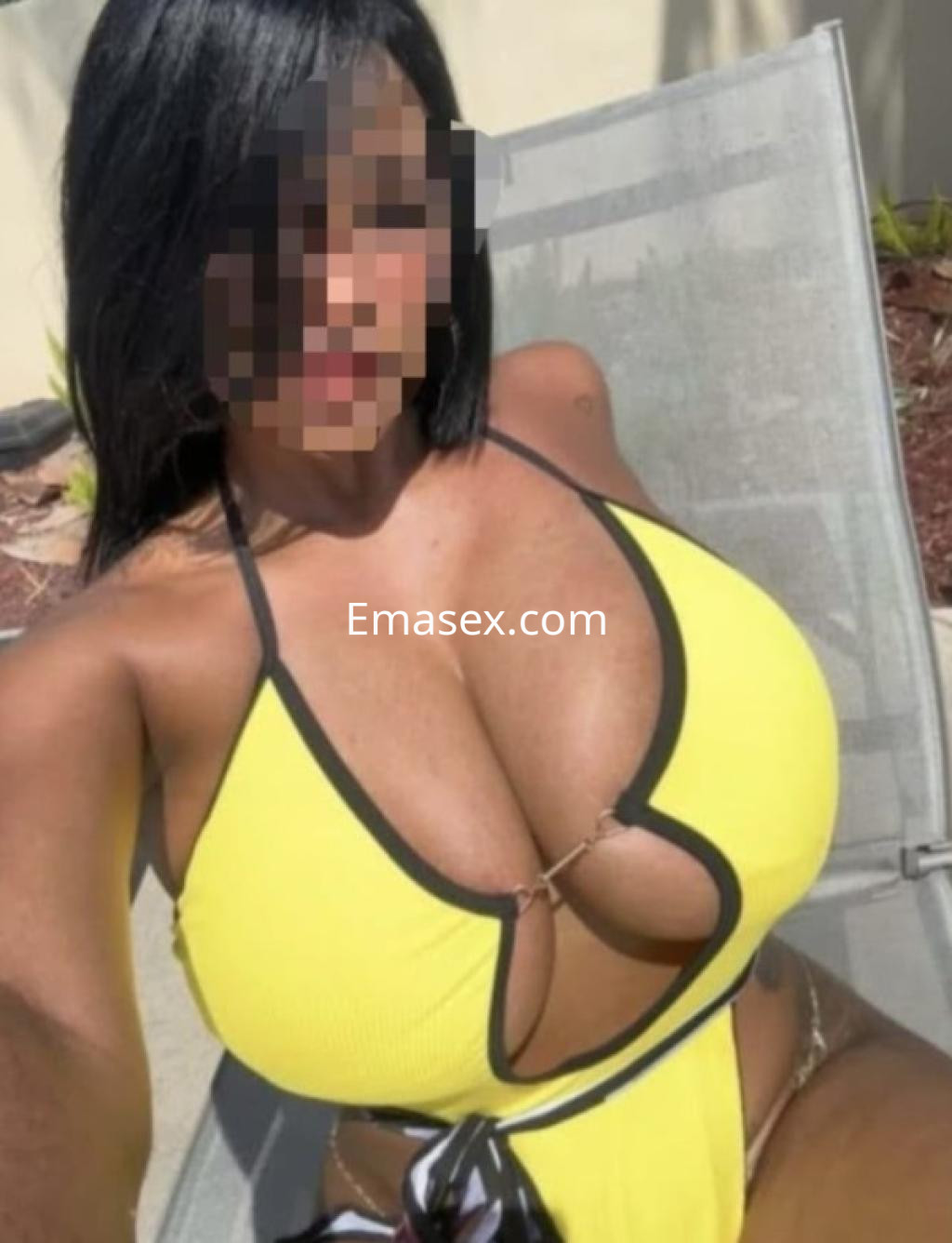 Puta en Burgos luce un traje de baño amarillo ajustado, posando sentada en una silla al aire libre.