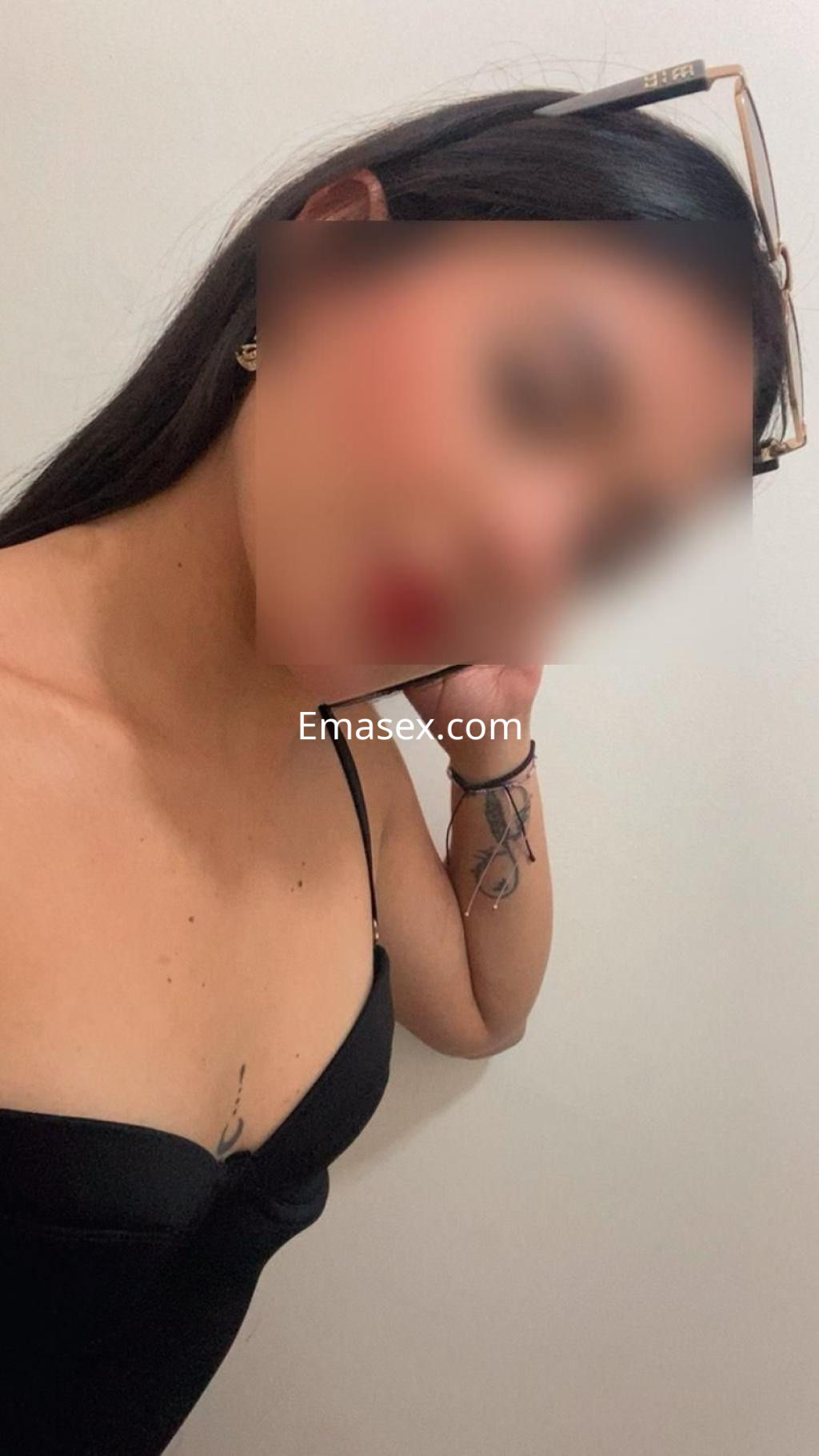 Puta en Cáceres con blusa negra ajustada, luciendo pendientes y un tatuaje visible en el brazo.