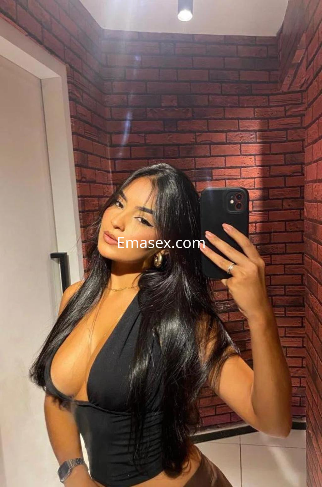 Puta con cabello largo y lacio, viste un top negro que resalta su figura mientras se toma un selfie en Granada.