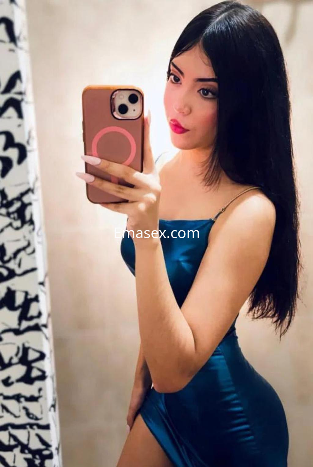 Escort en Granada con cabello largo y lacio, luciendo un vestido ajustado de color azul en un baño.