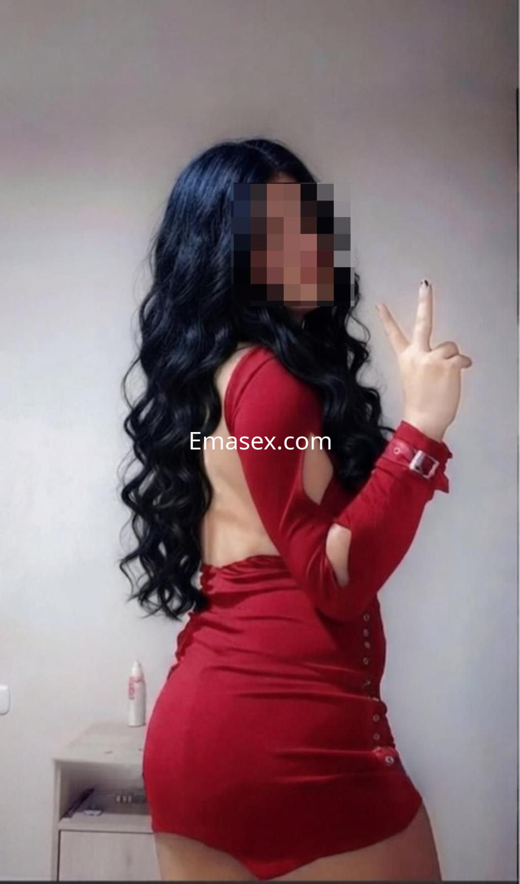 La puta en León viste un vestido rojo ajustado que resalta su figura, con cabello largo y ondulado.