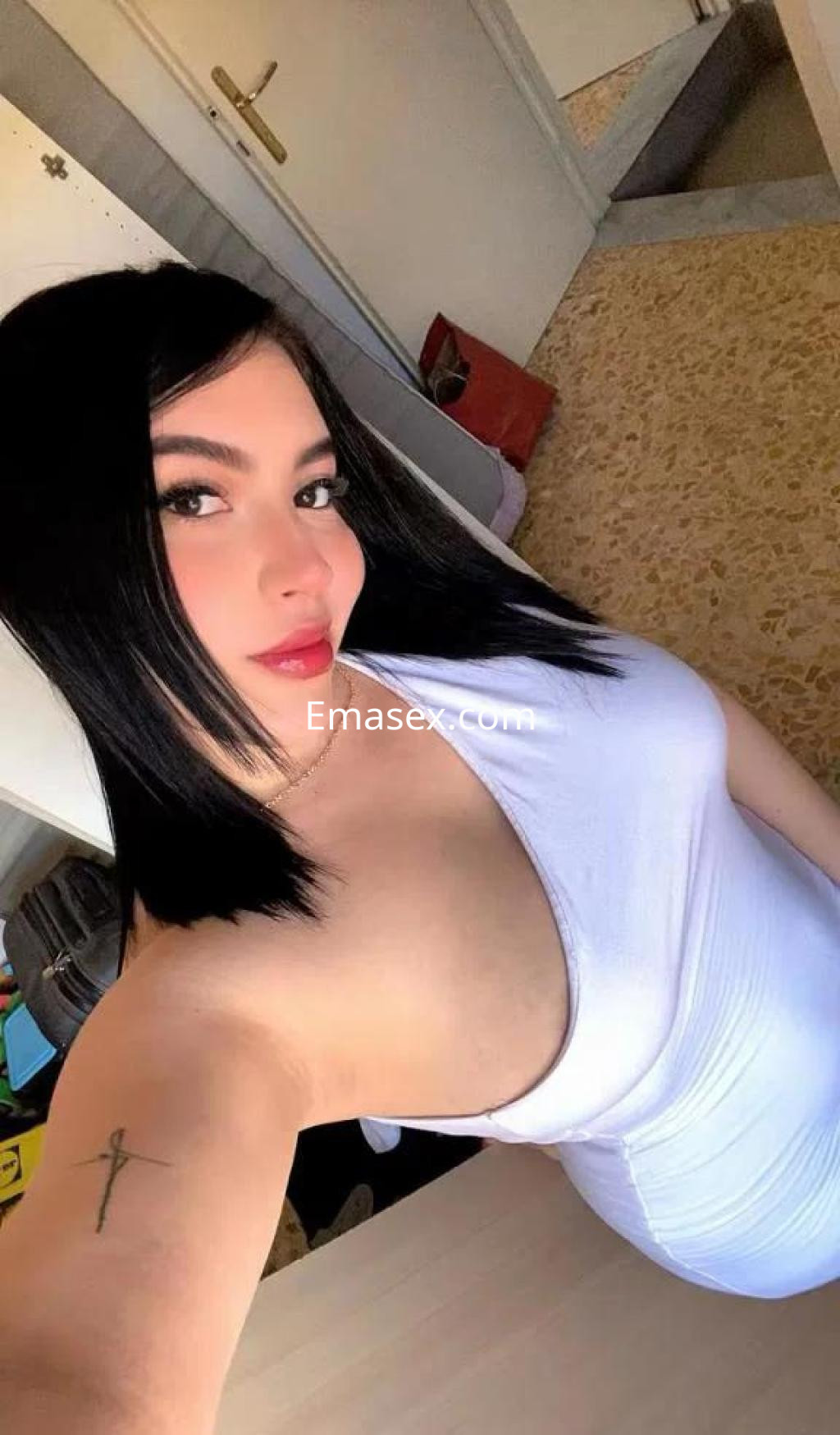 Escort en Lleida con cabello negro y lacio, vistiendo un vestido blanco ajustado que resalta su figura.