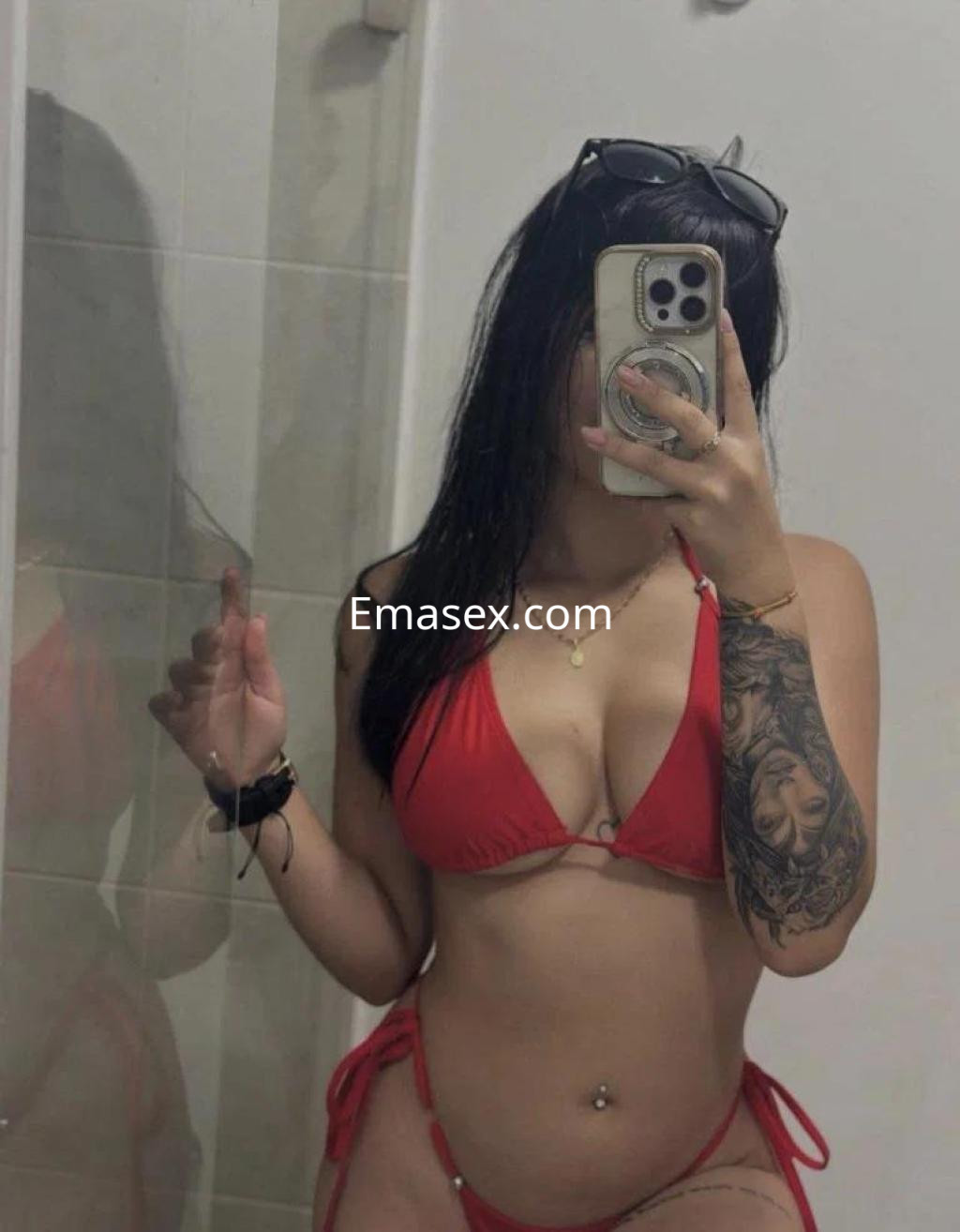 Puta con bikini rojo y gafas de sol, posando frente al espejo en un baño de Madrid.