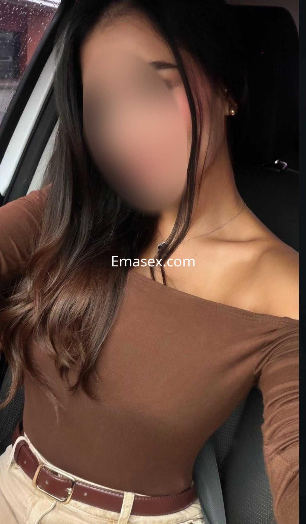 Puta con cabello oscuro y lacio, viste una blusa marrón y pantalones claros, posando en un coche en Tarragona.