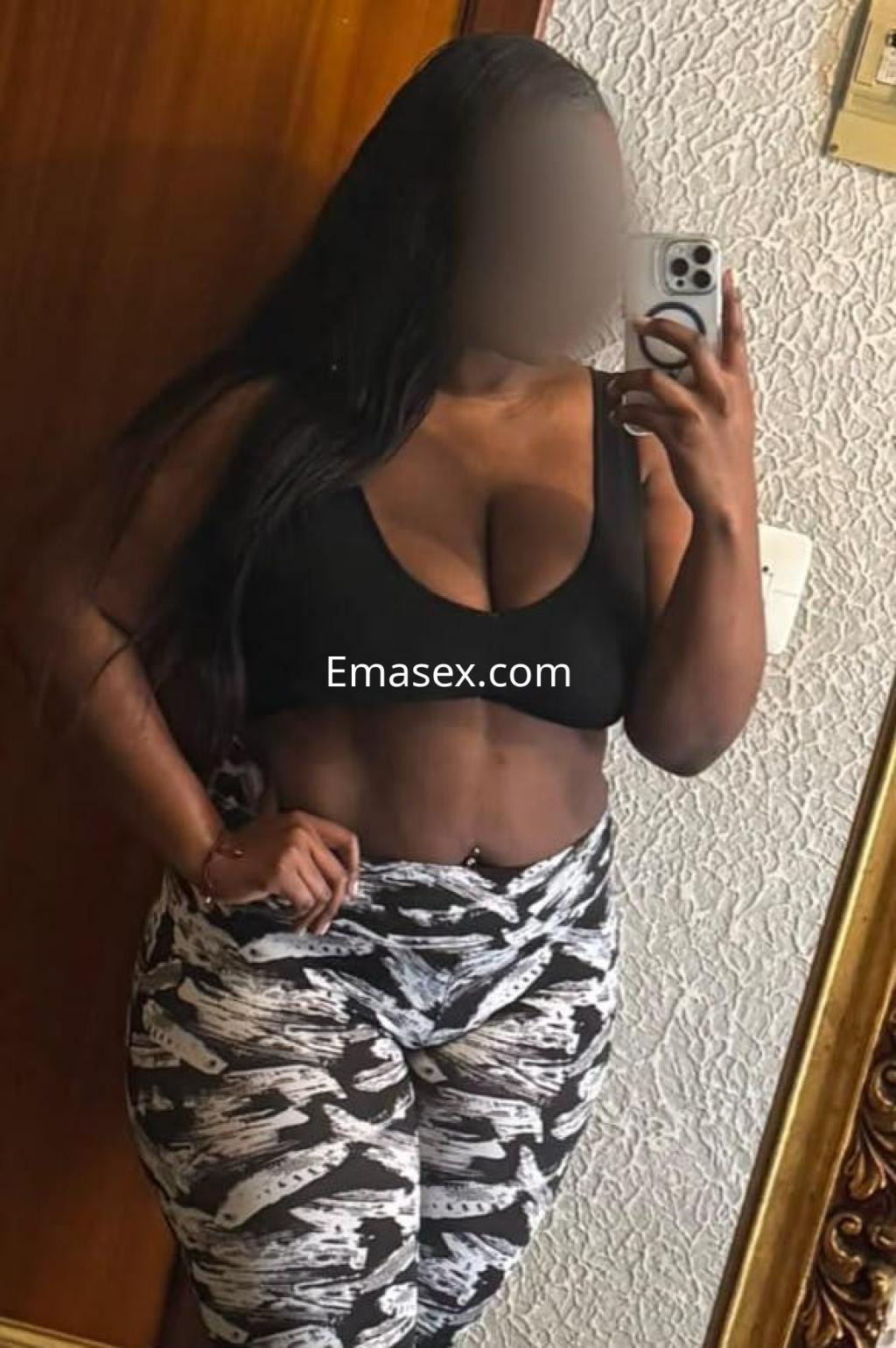 Puta posando frente al espejo con top negro y leggins estampados en una habitación de Valencia.