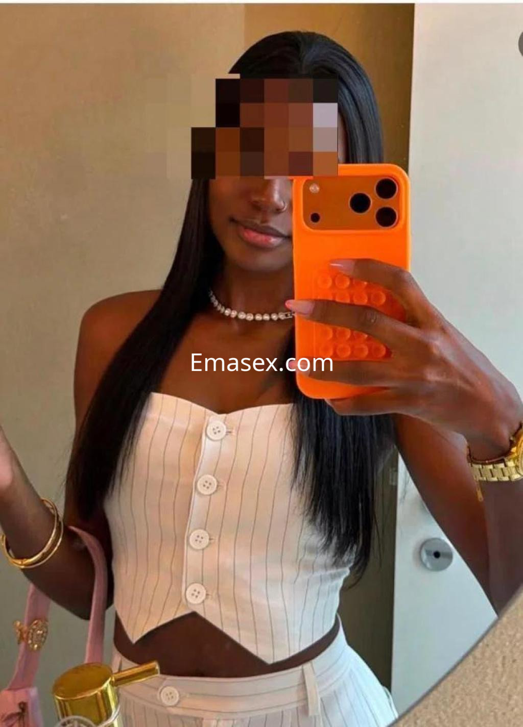 La escort en Valencia se muestra en un espejo luciendo un top sin mangas de rayas y un pantalón blanco.