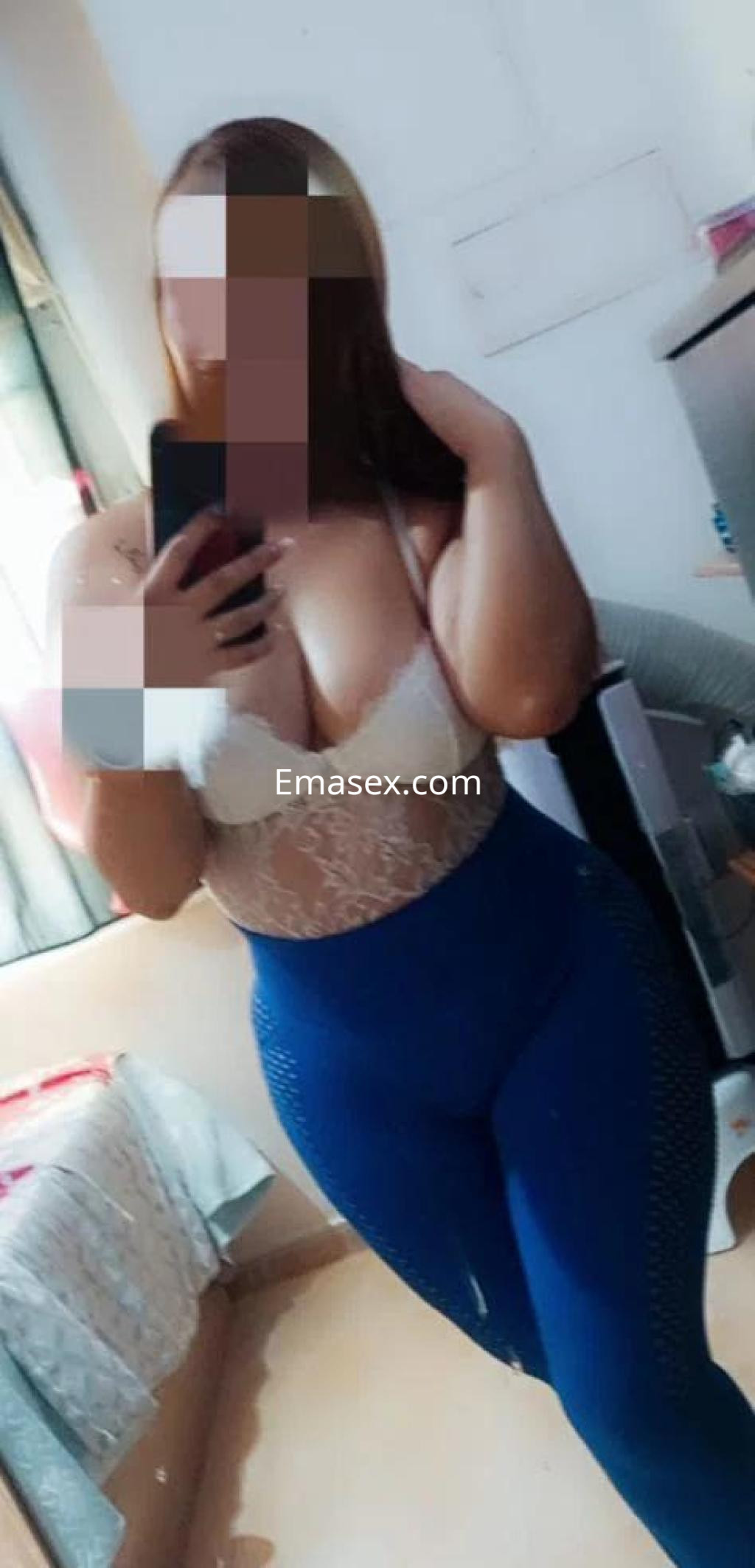 Escort en Valencia posando frente a un espejo, vistiendo un top blanco y leggings azules ajustados.