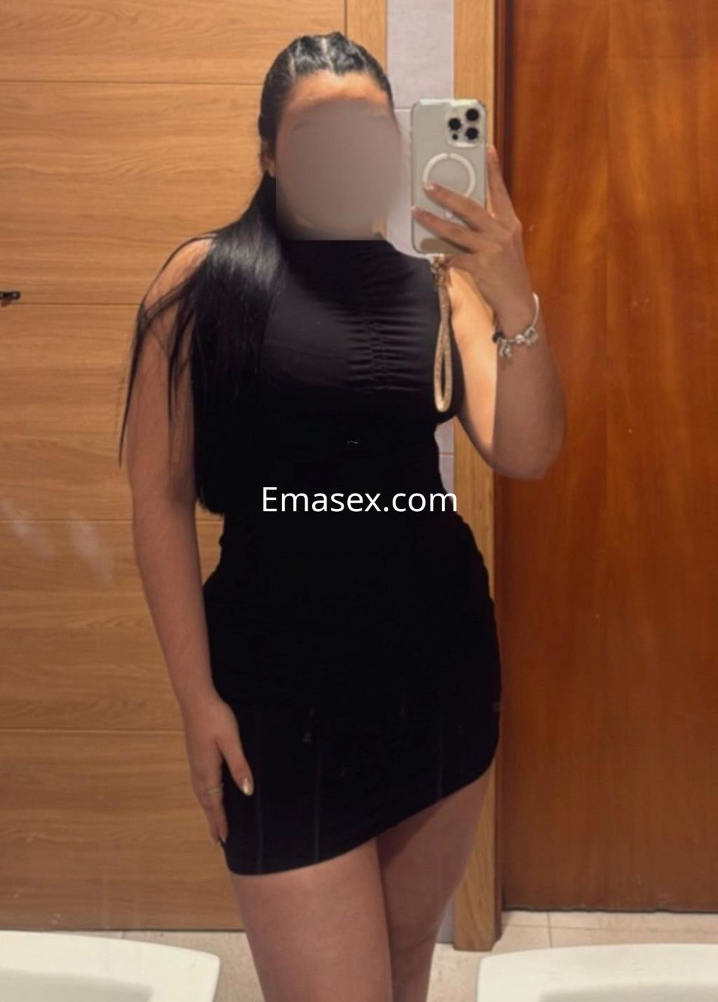 Puta en Vigo, posando en un espejo con un vestido negro ajustado que resalta su figura.