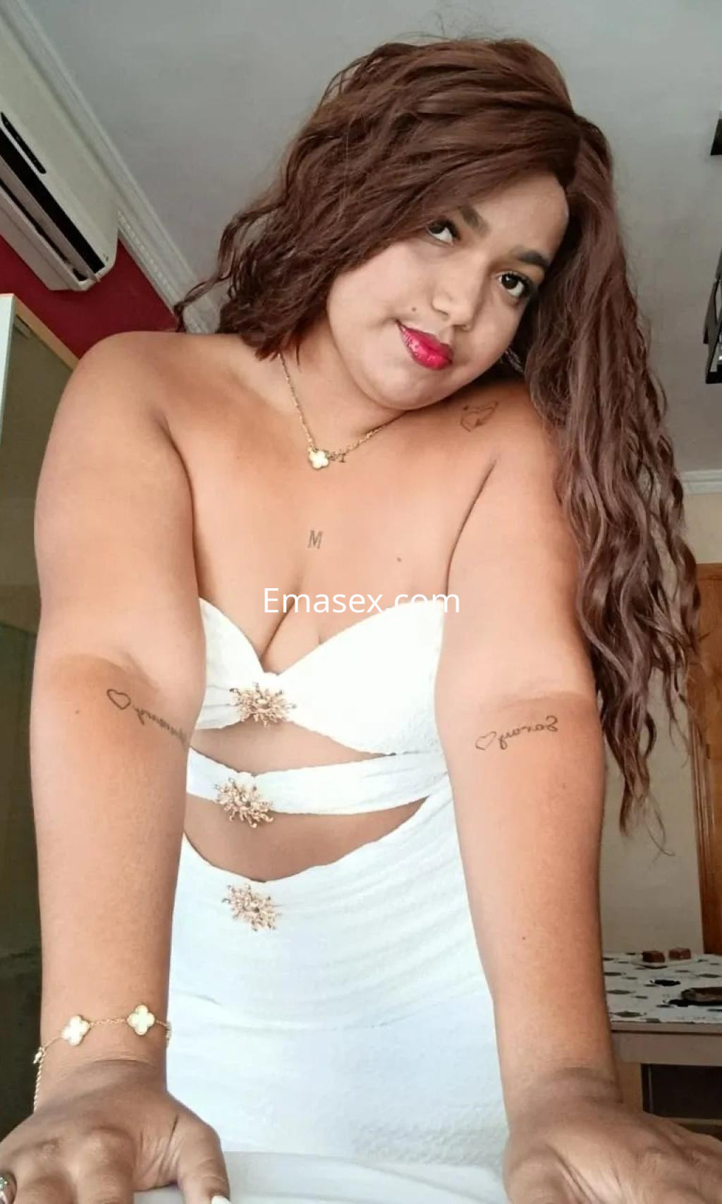 Escort en Málaga con cabello largo y castaño, viste un vestido blanco ajustado y se muestra de forma seductora.