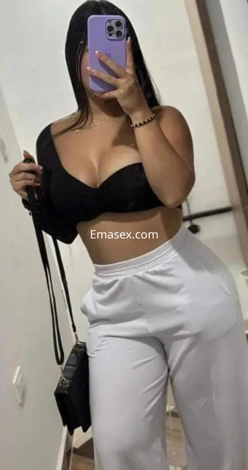 La puta en Coruña se muestra con un top negro y pantalones blancos, destacando su figura y cabello lacio.