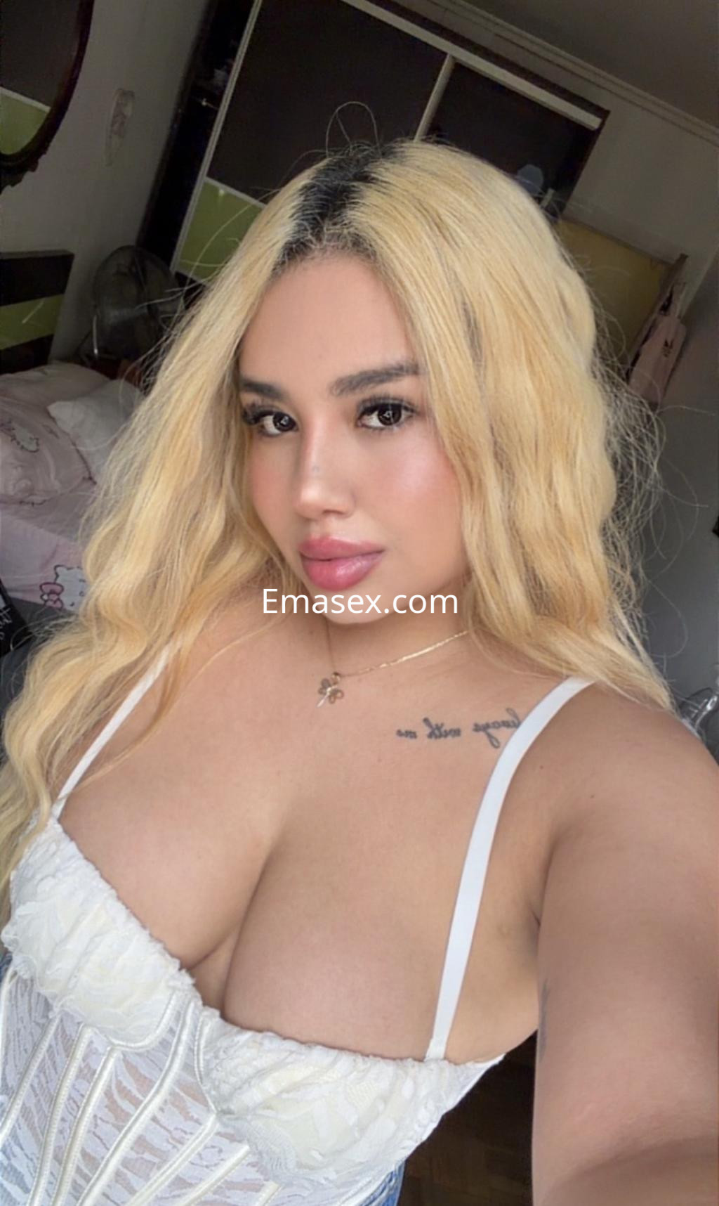 Puta en Donosti con corset blanco y cabello largo y ondulado, posando con una sonrisa en un entorno interior.