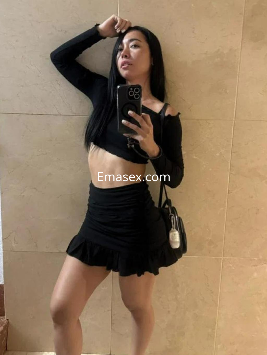Escort en Castellón posando con una blusa negra de manga larga y una falda corta, mostrando su figura.