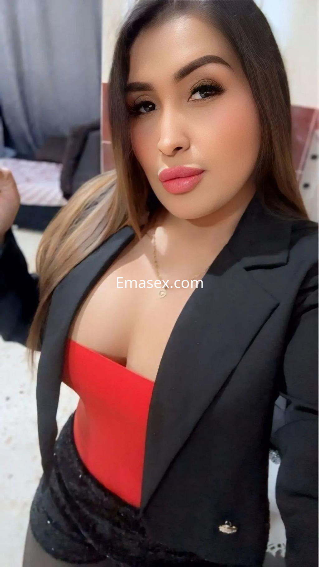 Puta posando en Alicante con un vestido rojo ajustado y chaqueta negra, mostrando un look elegante y seductor.