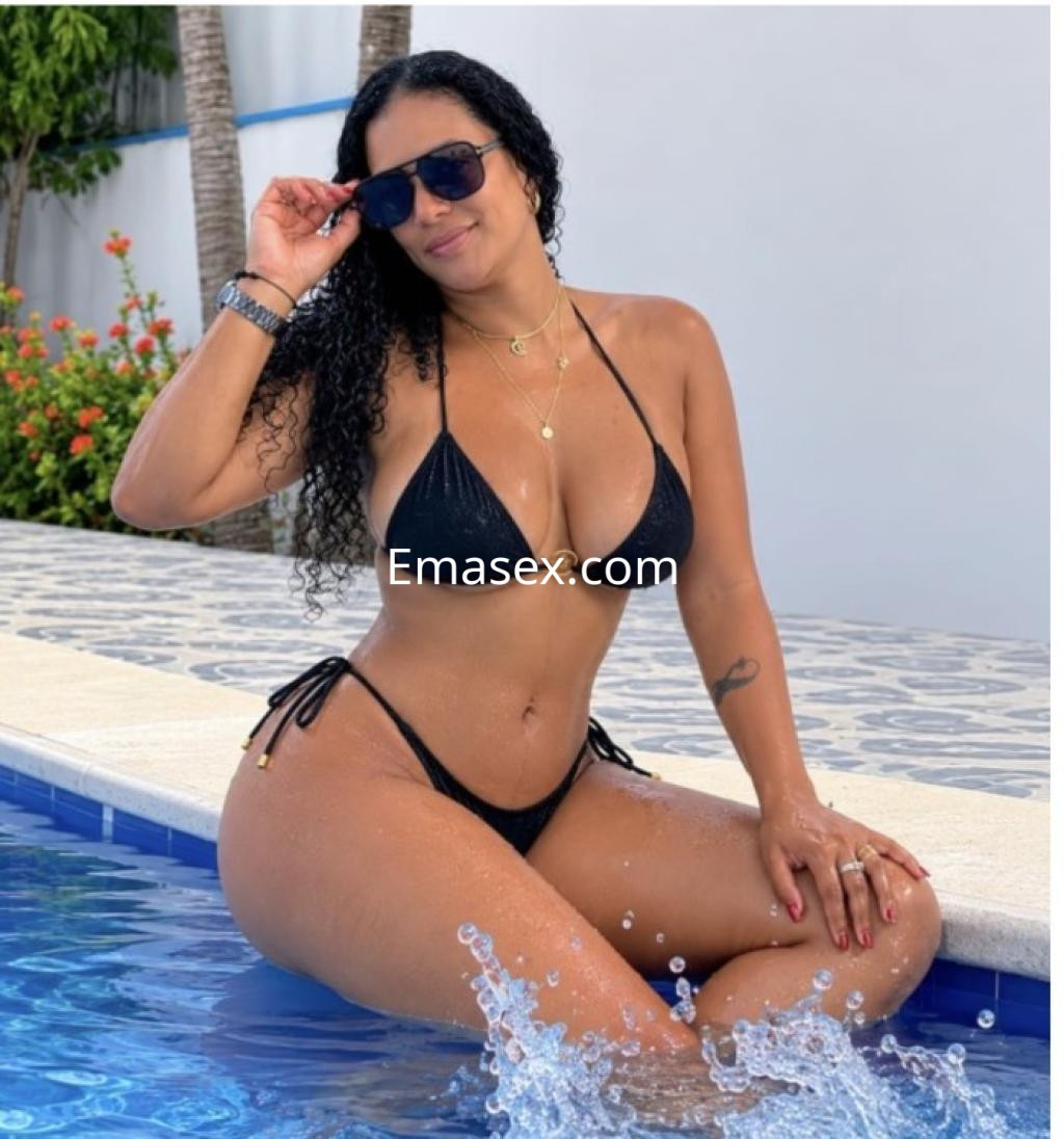 Puta posando en la piscina con un bikini negro, gafas de sol y cabello rizado, en Santiago.