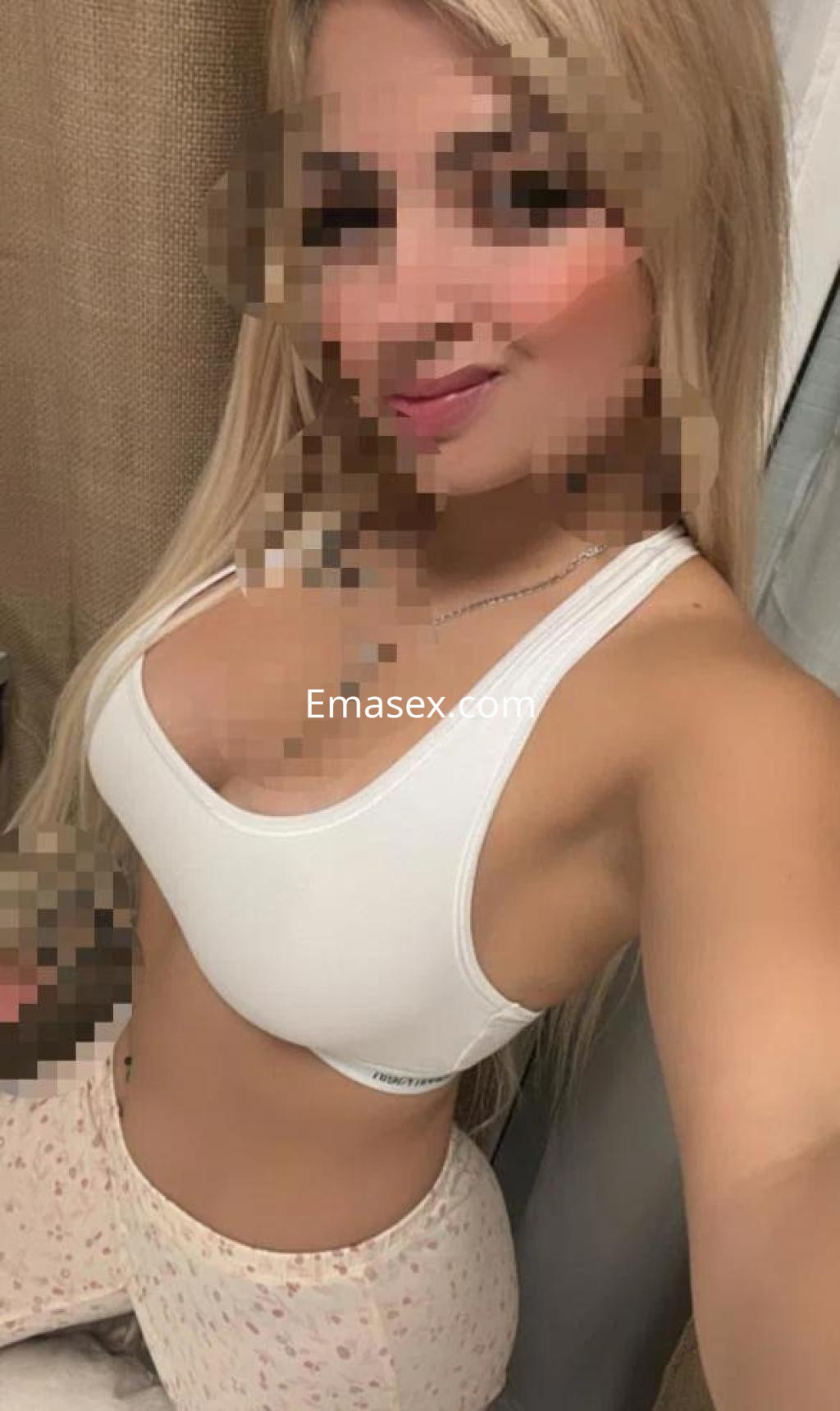 La puta posa con una camiseta blanca y pantalones de pijama claros en un entorno acogedor en Girona.