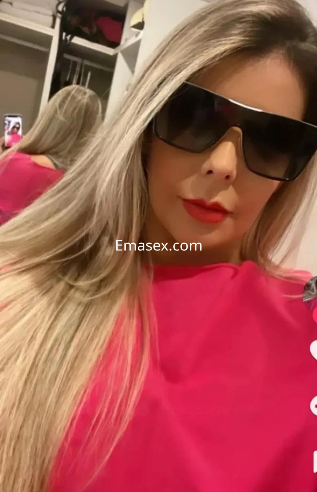 Puta con cabello largo y rubio, usando gafas oscuras y blusa rosa, en un entorno interior en Granada.