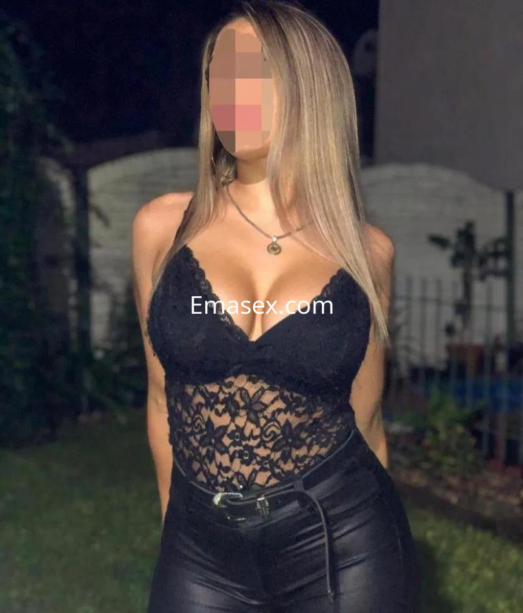 Escort en Lugo luciendo un body negro de encaje y pantalones ajustados, con cabello largo y lacio.