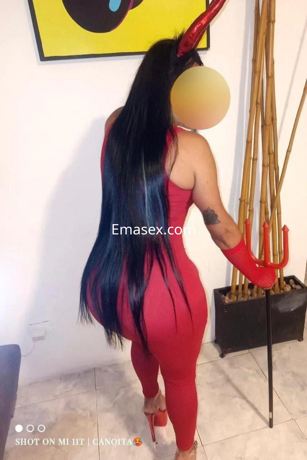 Puta de cabello largo y lacio, vestida con un ajustado traje rojo y tacones altos, posando en un ambiente moderno en Murcia.