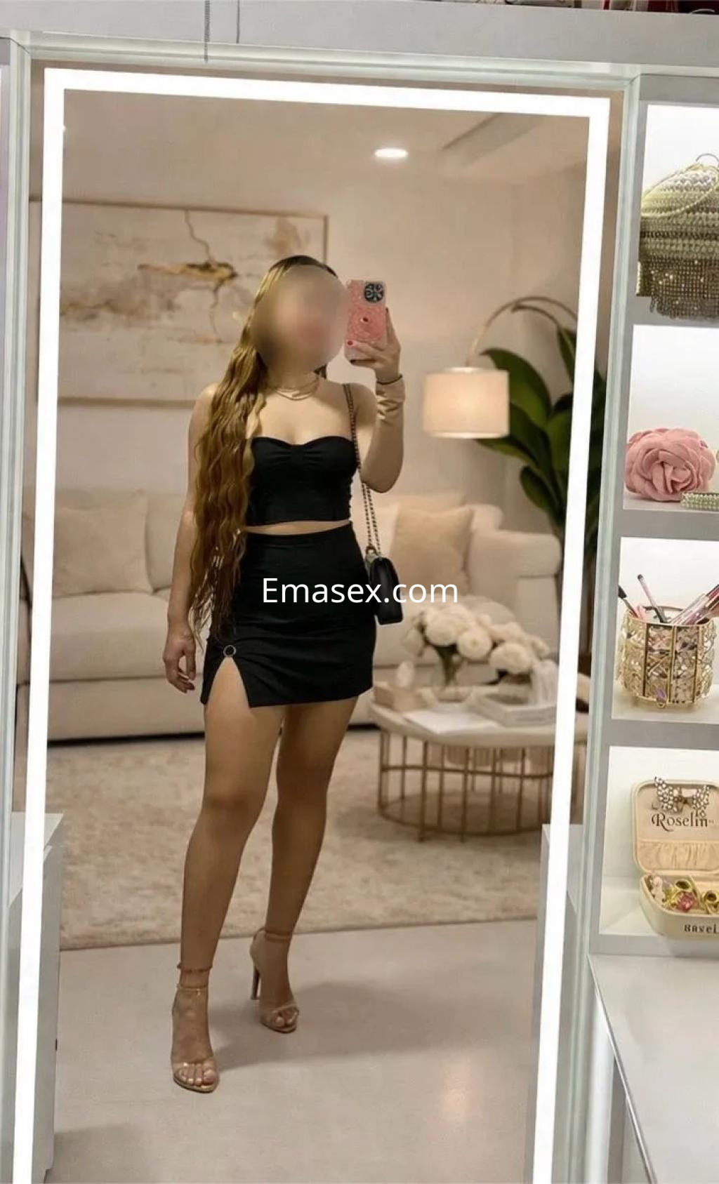 Puta con cabello largo y lacio, vestida con un top negro y falda corta, posando en un ambiente moderno en Murcia.
