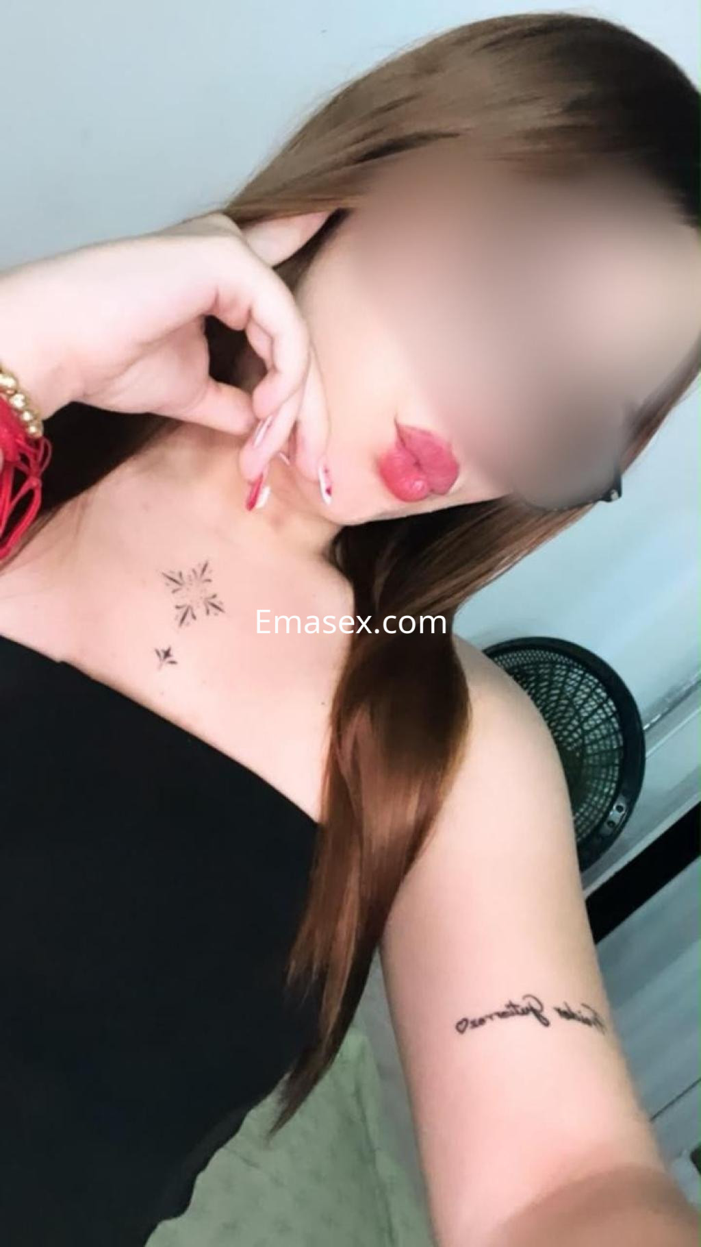 Escort en Pamplona con cabello largo y lacio, luciendo un top negro y mostrando un tatuaje en el brazo.